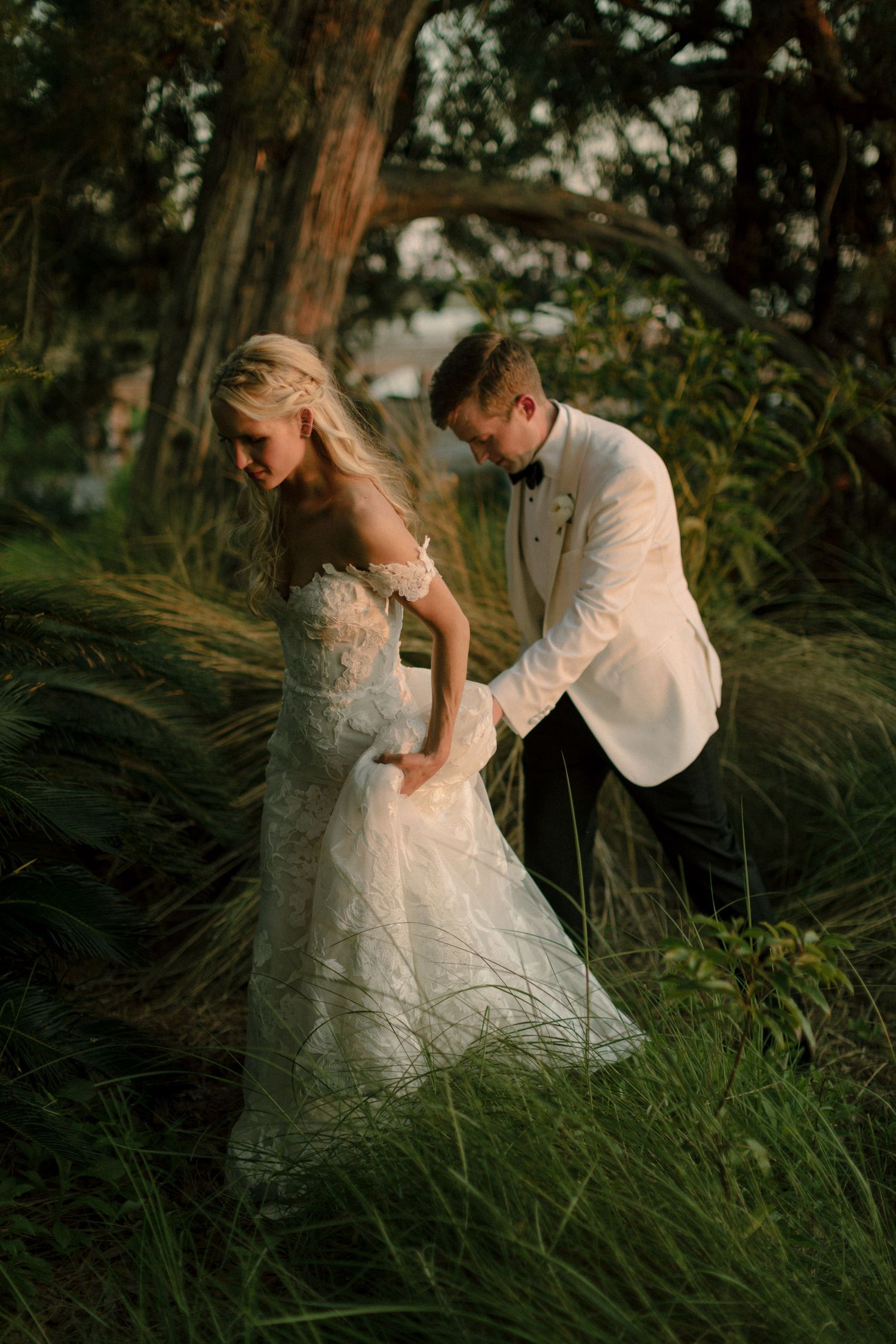 Romantic sunset portrait of couple in tall grass with white wedding attire.