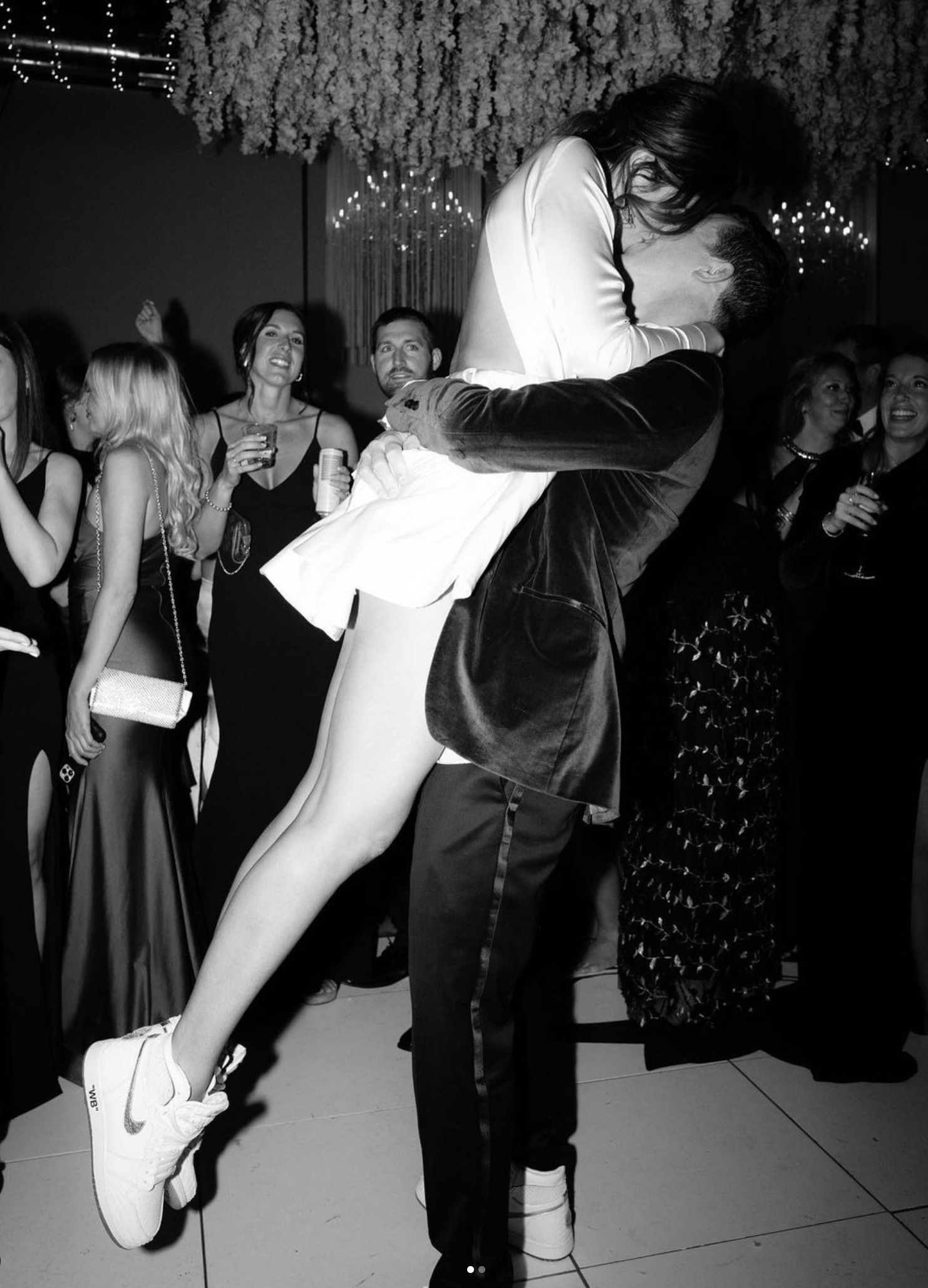 A celebratory dance moment at a wedding reception captured in dramatic black and white.