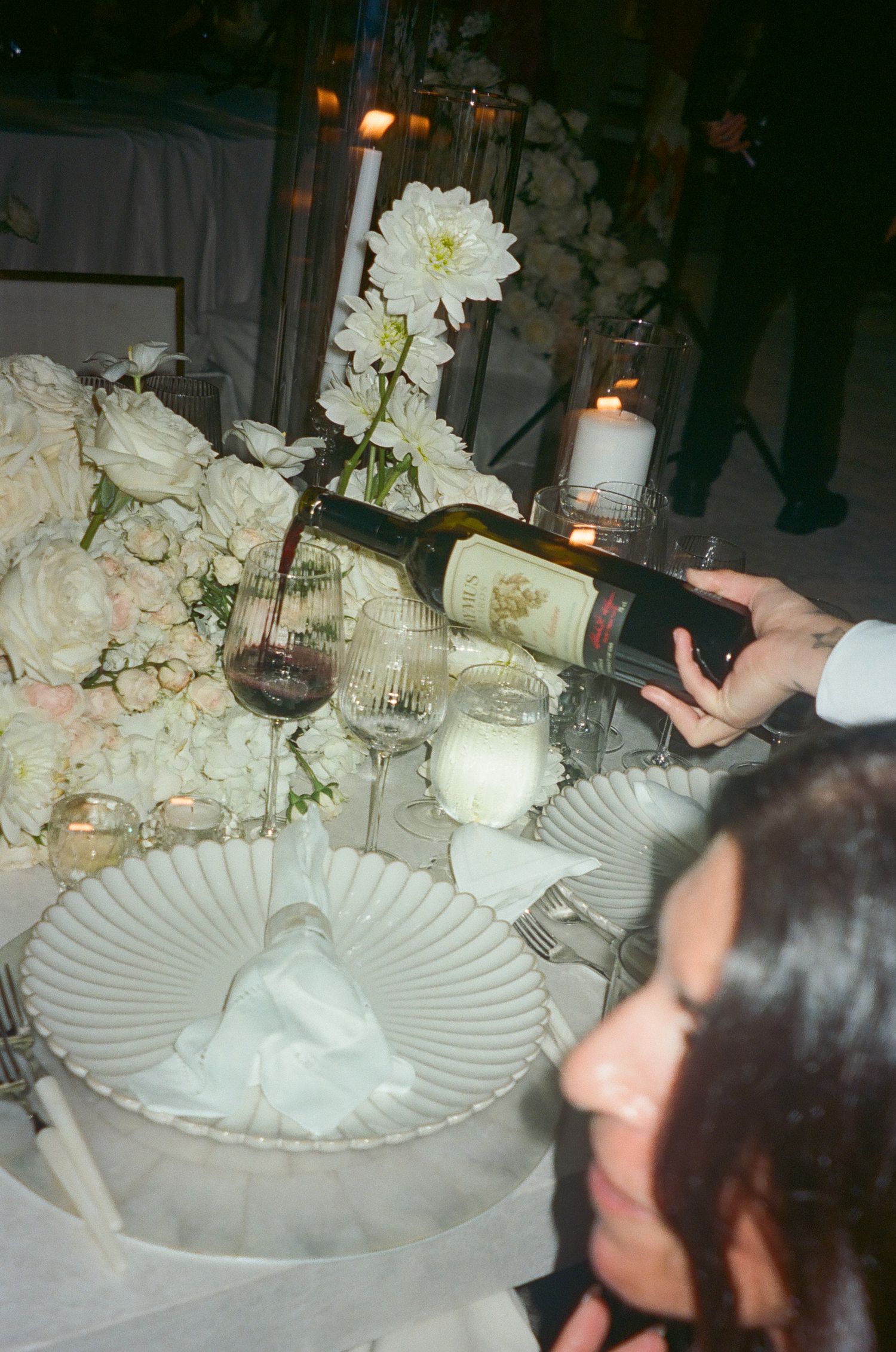 White floral centerpieces and elegant place settings adorn a formal dining table with candlelight.