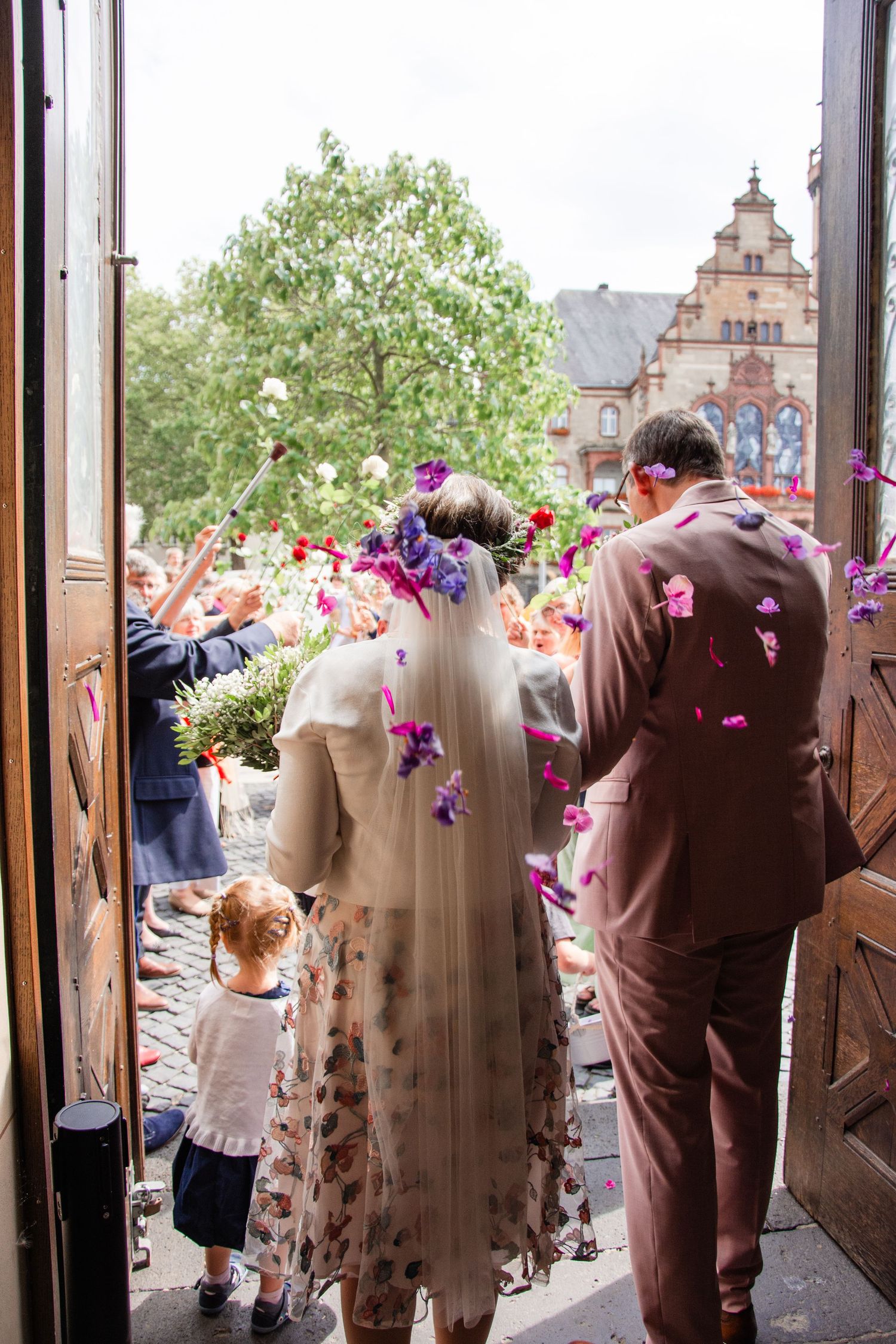 Hochzeitspaar beim Auszug aus der Kirche, Blumen in der Luft, rosa Anzug, Mönchengladbach