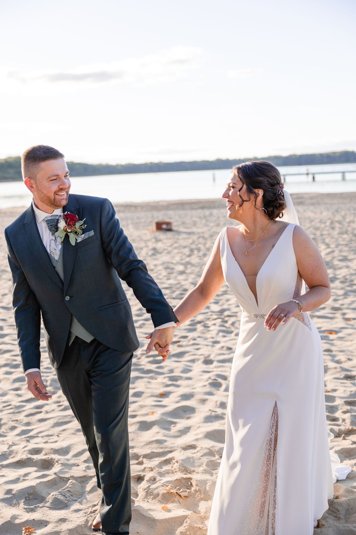 Brautpaar lachend am Strand Hände haltend sich anblickend beim Sonnenuntergangsshooting bei einer Hochzeit in Neustadt-Glewe, MV