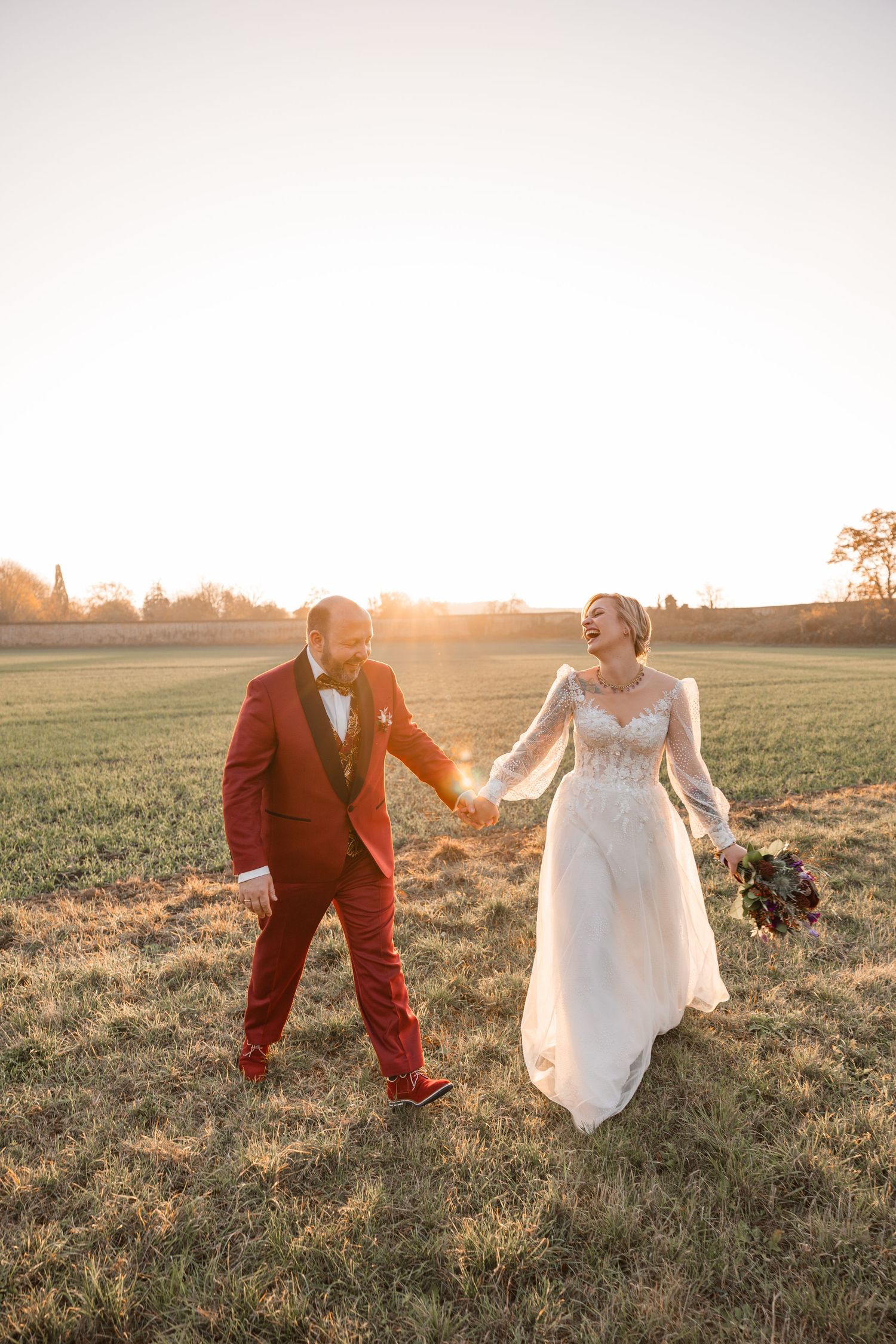 Lachendes Hochzeitspaar im Gegenlicht beim Paarshooting in Wöltingerode auf einer grünen Wiese