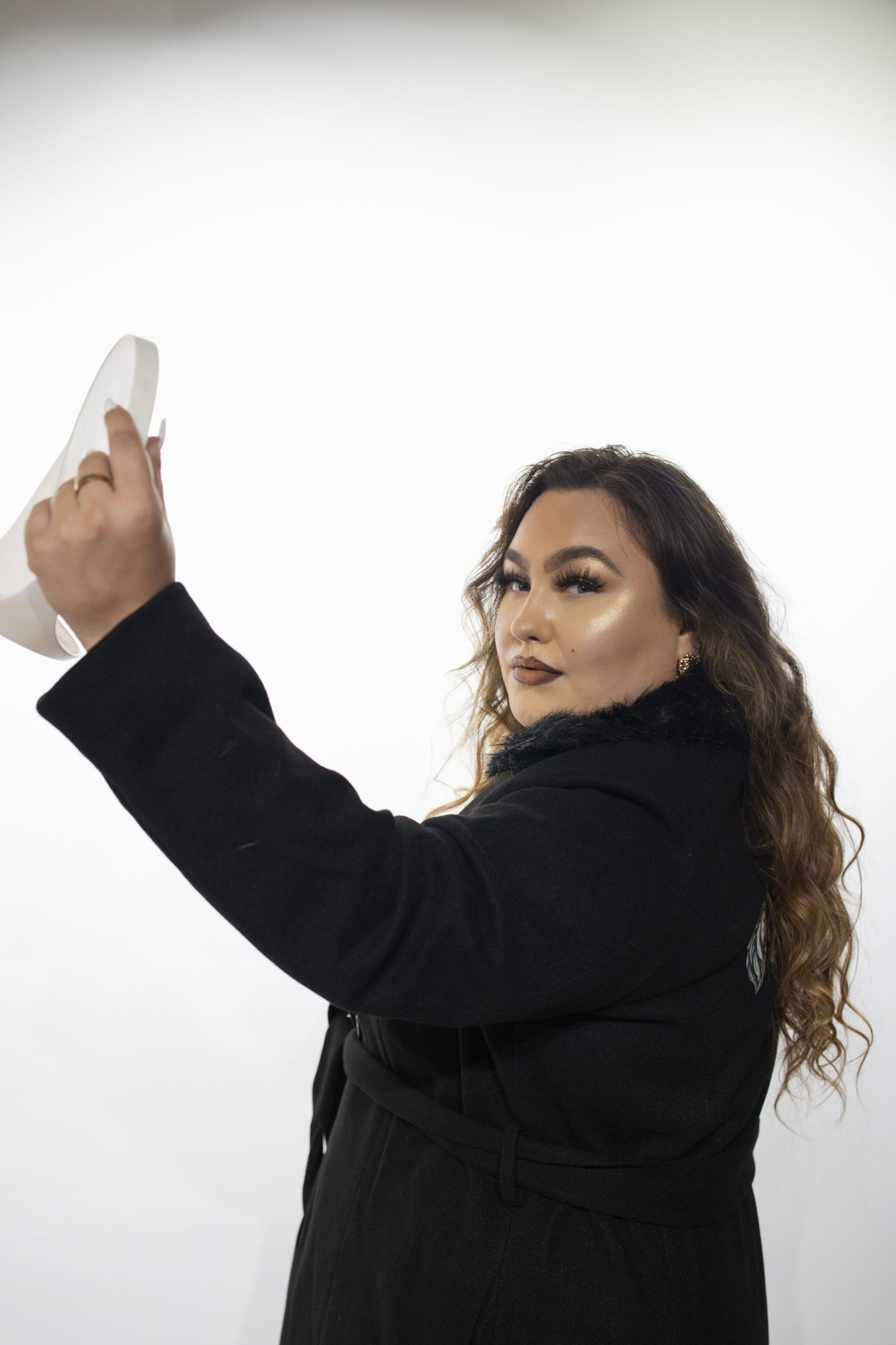 Person in black jacket making expressive dance movements against white background in sequence of poses.