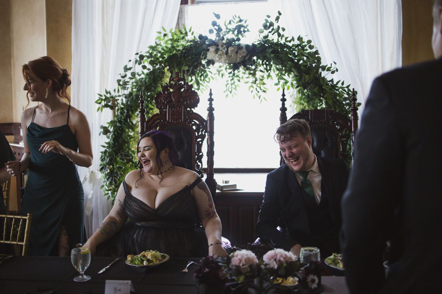 Wedding ceremony setting with elegant white drapes and green floral arch decorations.