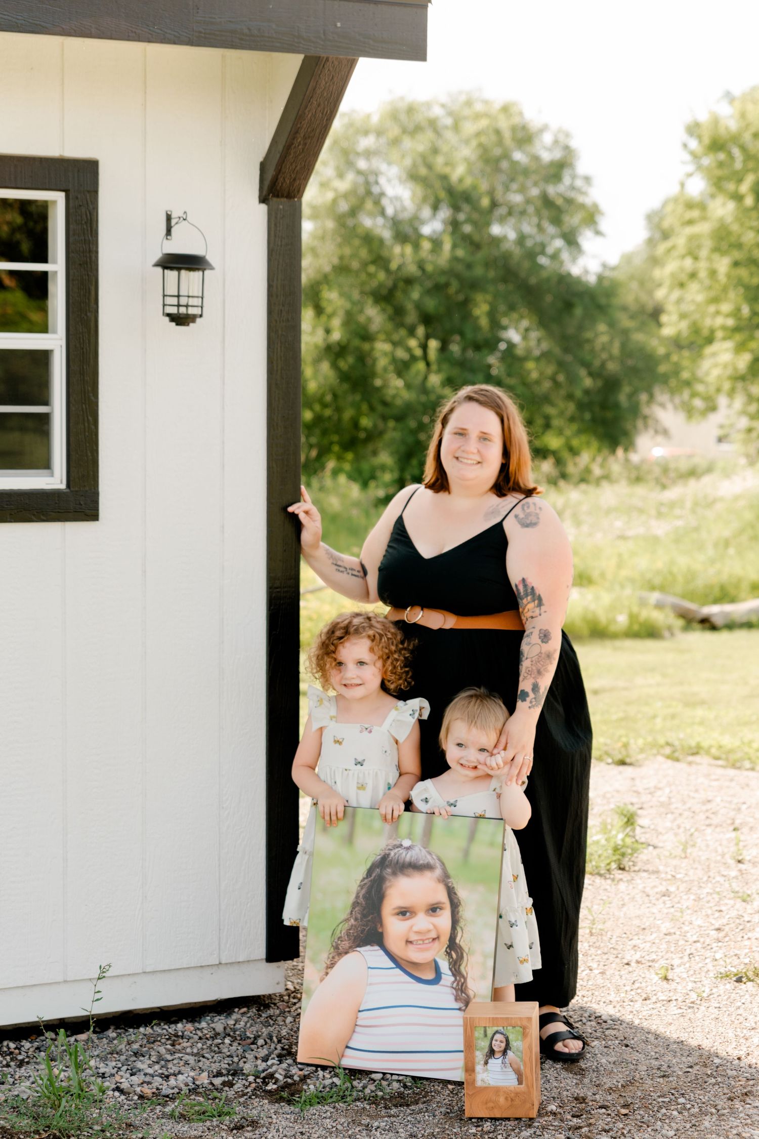 Family photo session outside white building with framed portrait and lantern on wall.