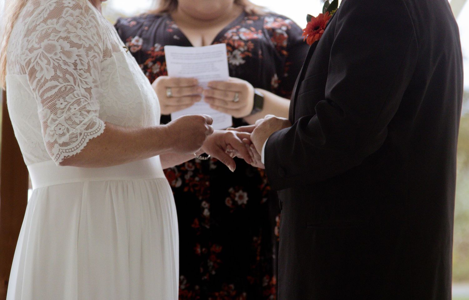 A close-up view of a bride and groom exchanging rings during an intimate wedding ceremony.