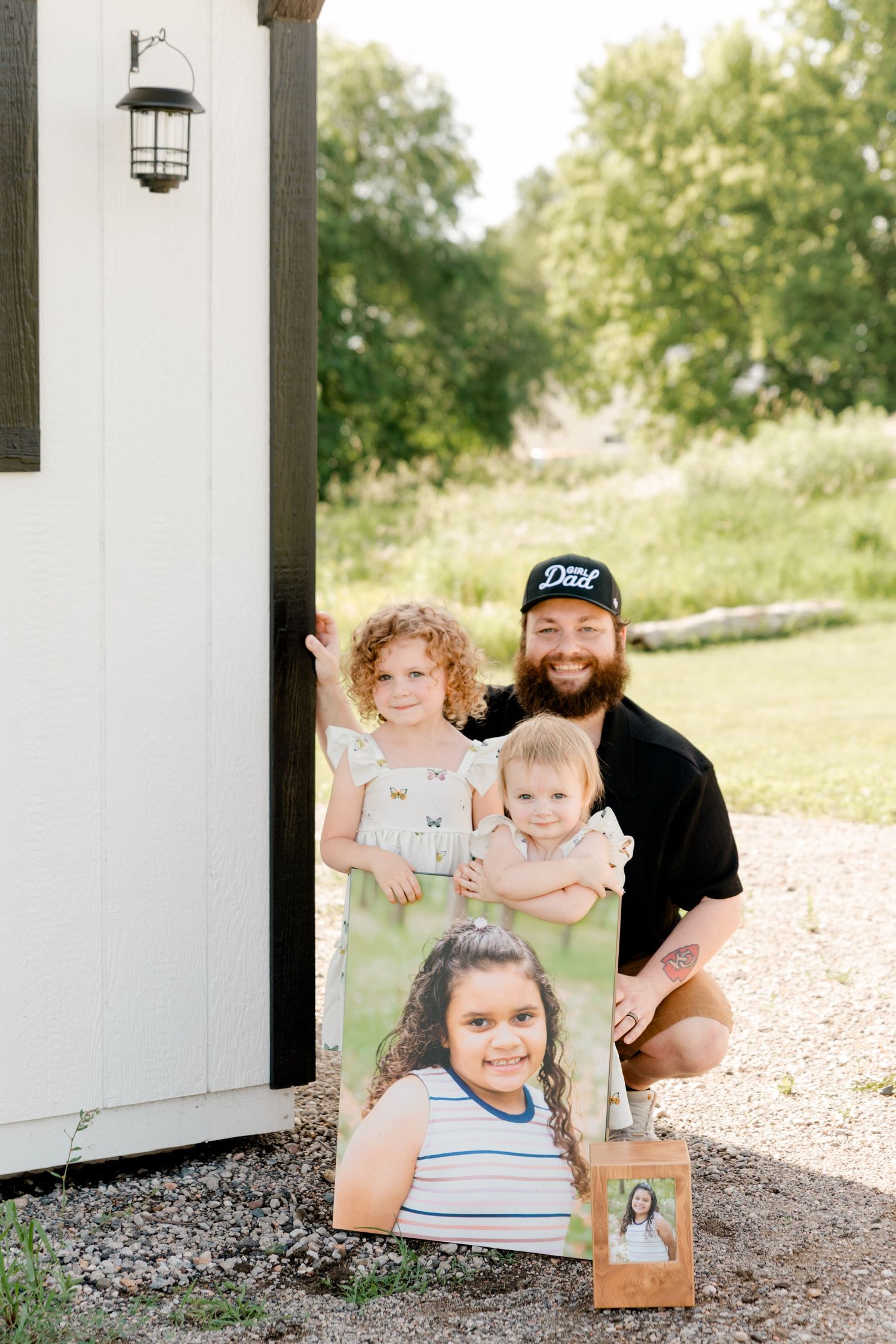 Family gathered outside white building with black-trimmed windows and decorative lantern.