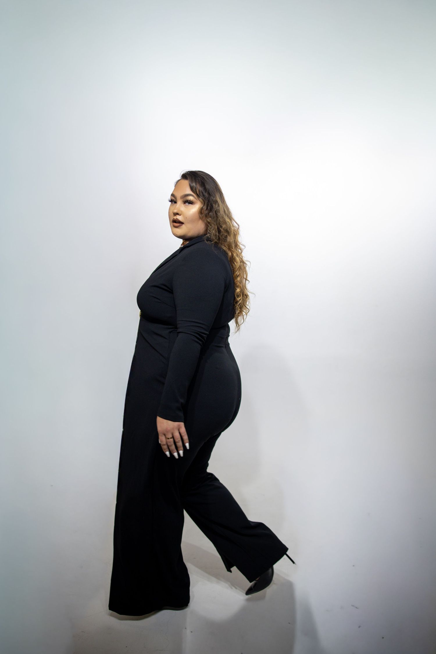 Artistic studio portrait series showing a figure in black attire moving dynamically against a white backdrop.
