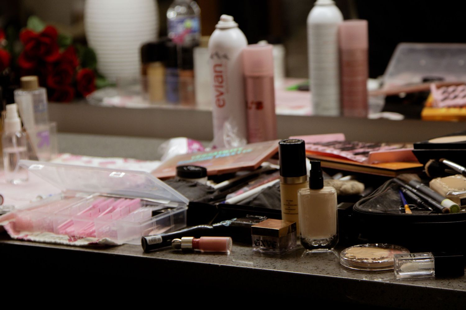 Makeup products and beauty supplies arranged on a dark counter surface.