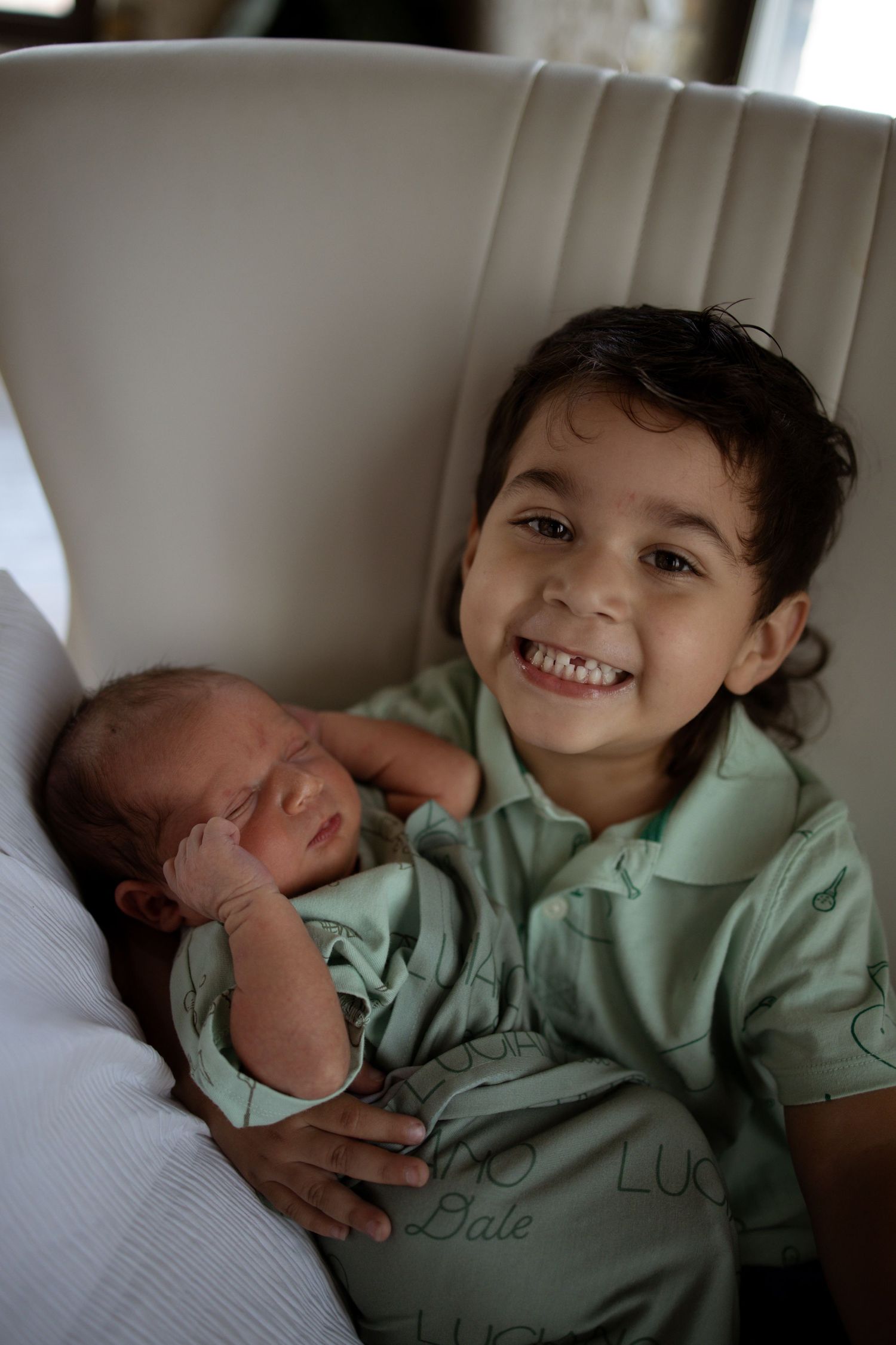 Four connected photos show sweet moments between siblings with the older child in mint green looking at a newborn baby.