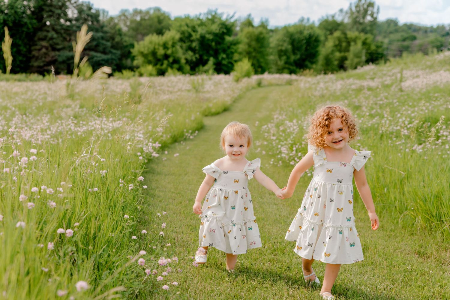 Small children playing in a summer meadow filled with blooming wildflowers on a sunny day.