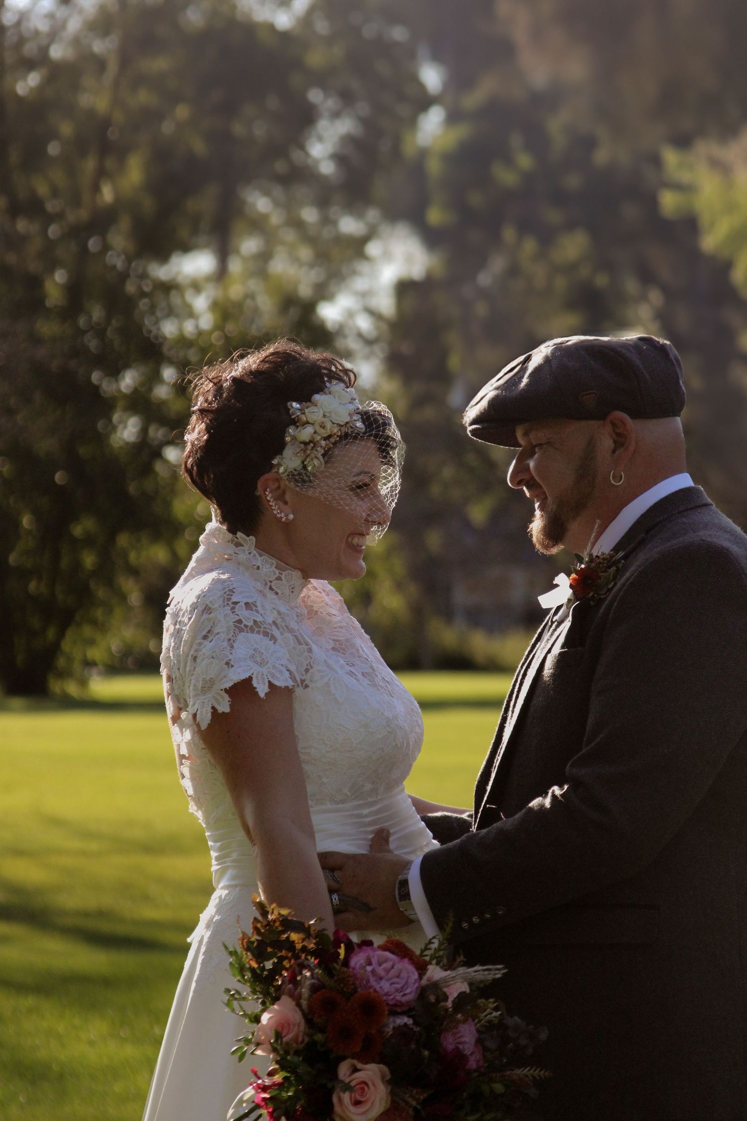 Couple shares an intimate moment outdoors against a sunny green backdrop during their wedding celebration.