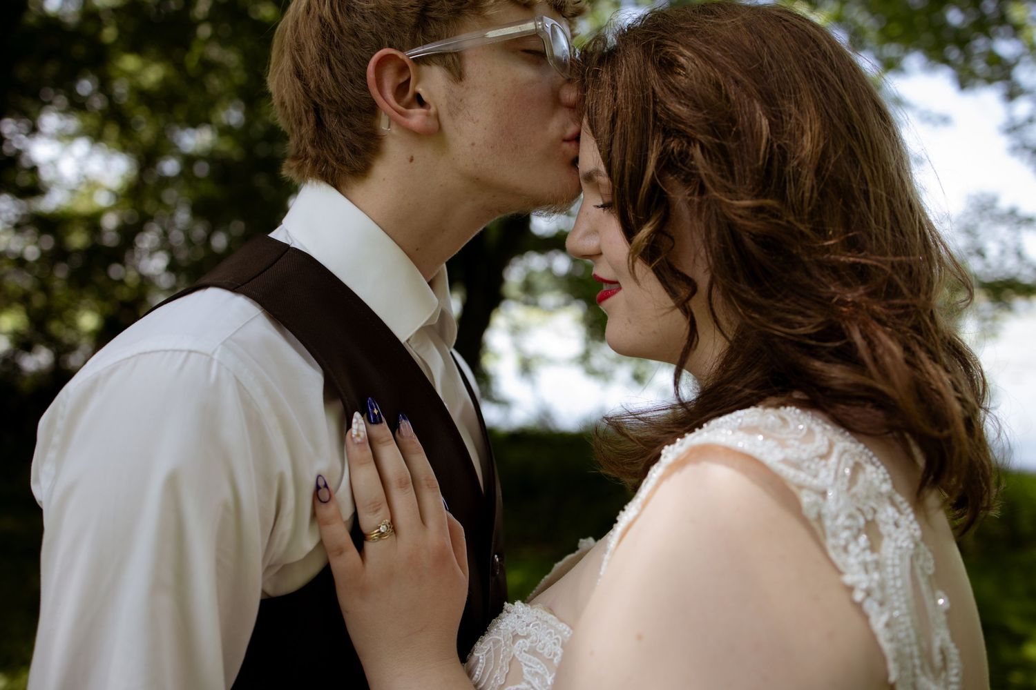 Intimate wedding photography moment of a bride and groom sharing a tender embrace outdoors in natural lighting.