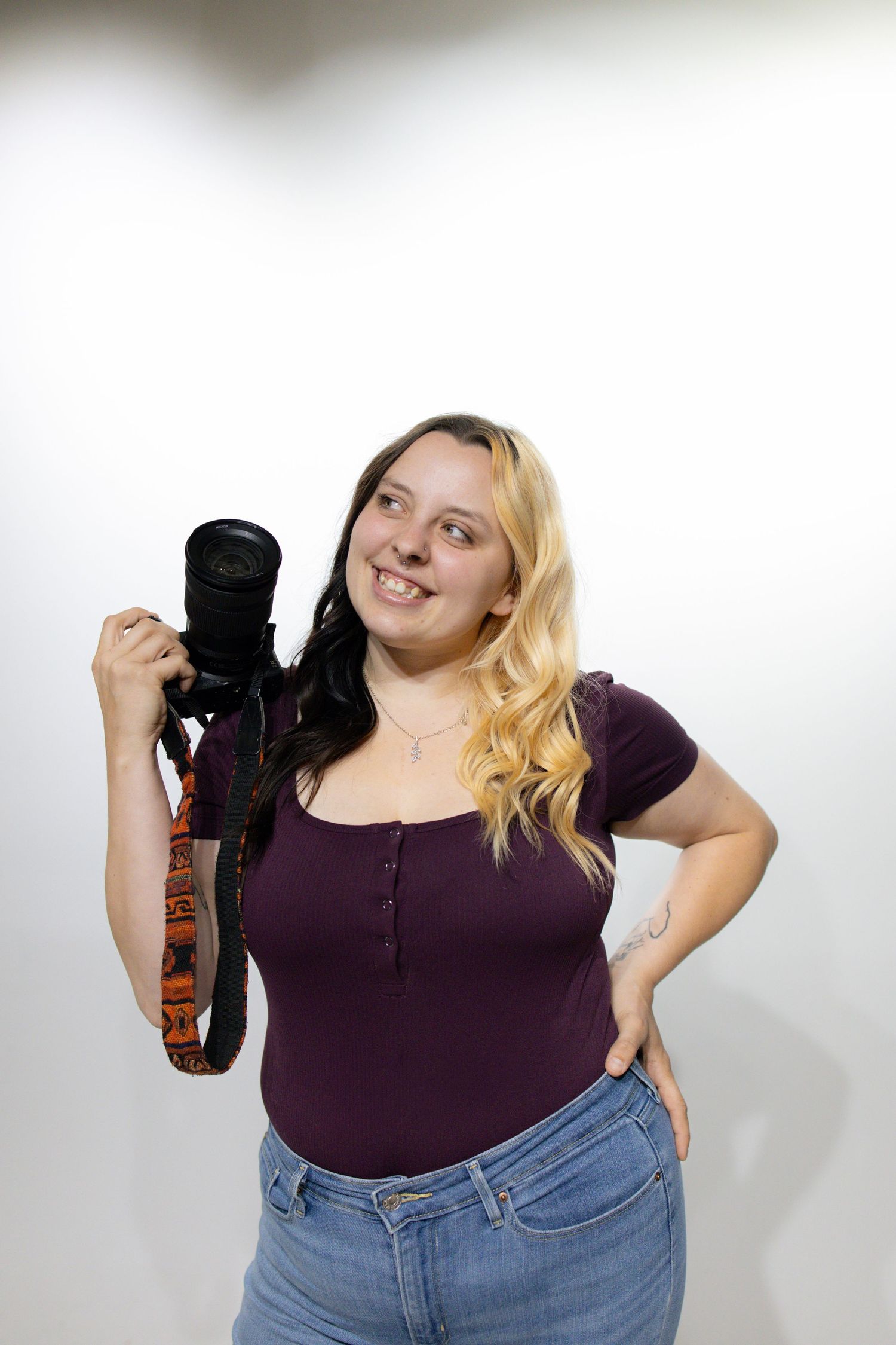 Plus-size model in purple top and jeans poses playfully against white background showing various expressions.