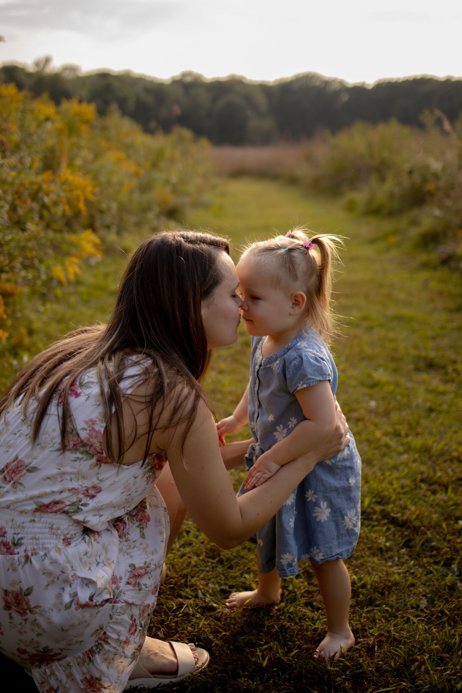 A tender moment is shared between parent and child in a sunlit meadow during golden hour.