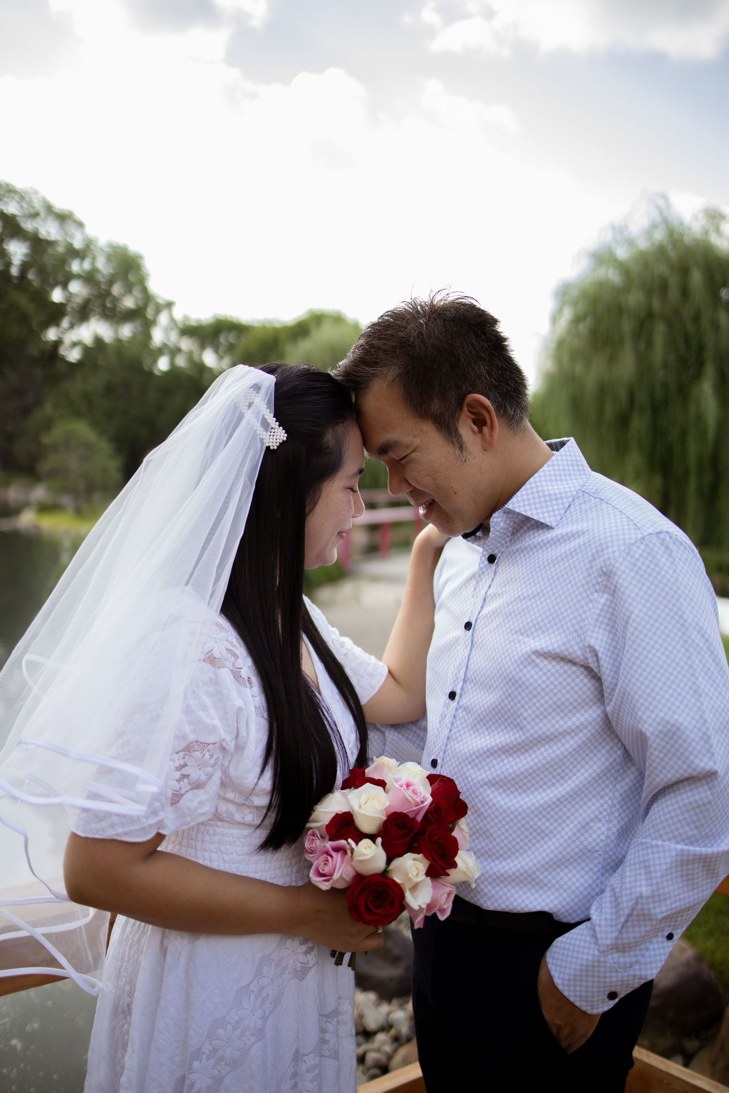 Romantic wedding couple shares intimate moments in a series of poses against a backdrop of willow trees.