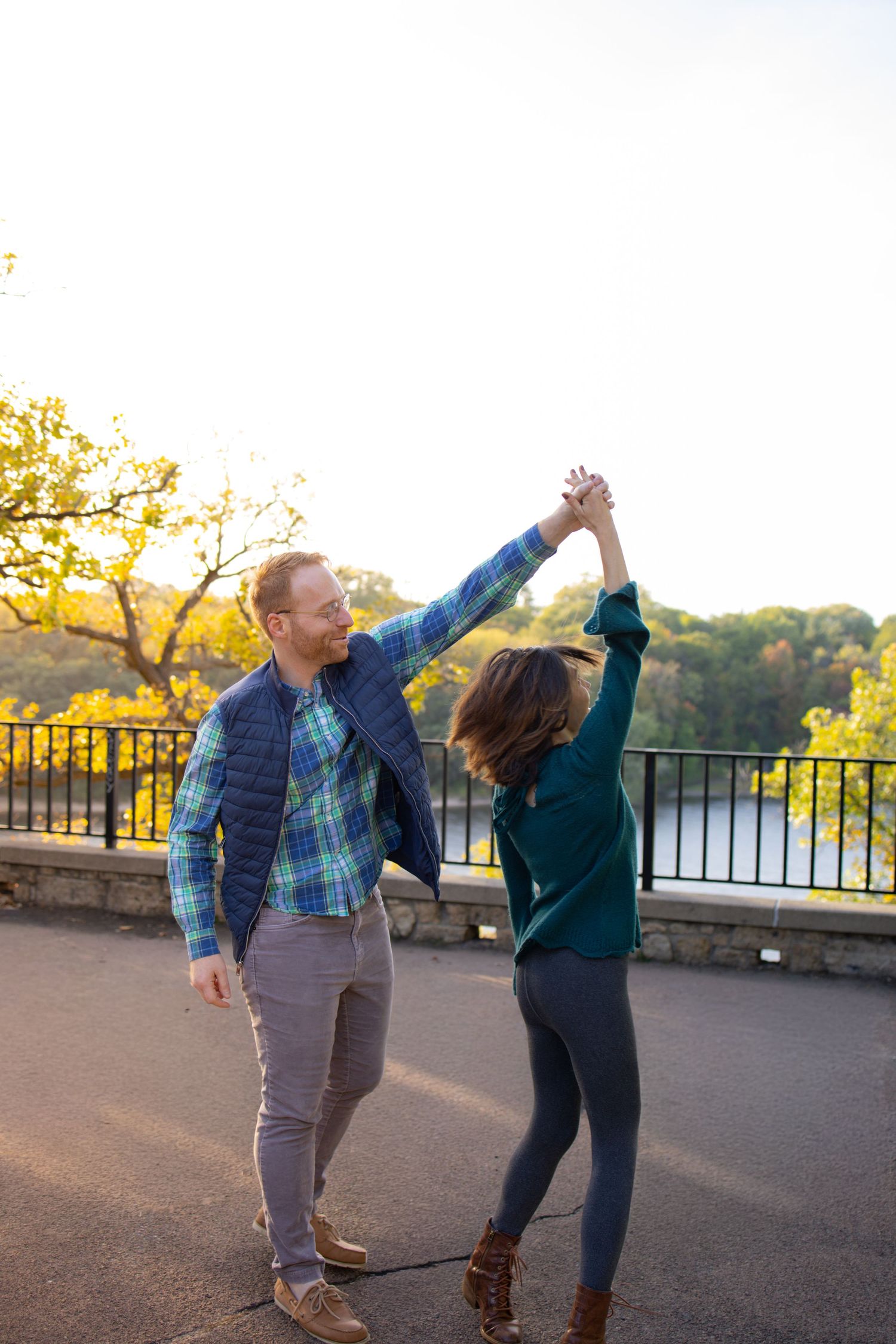 A couple dances together on a scenic overlook at sunset, creating a joyful moment in the golden hour light.