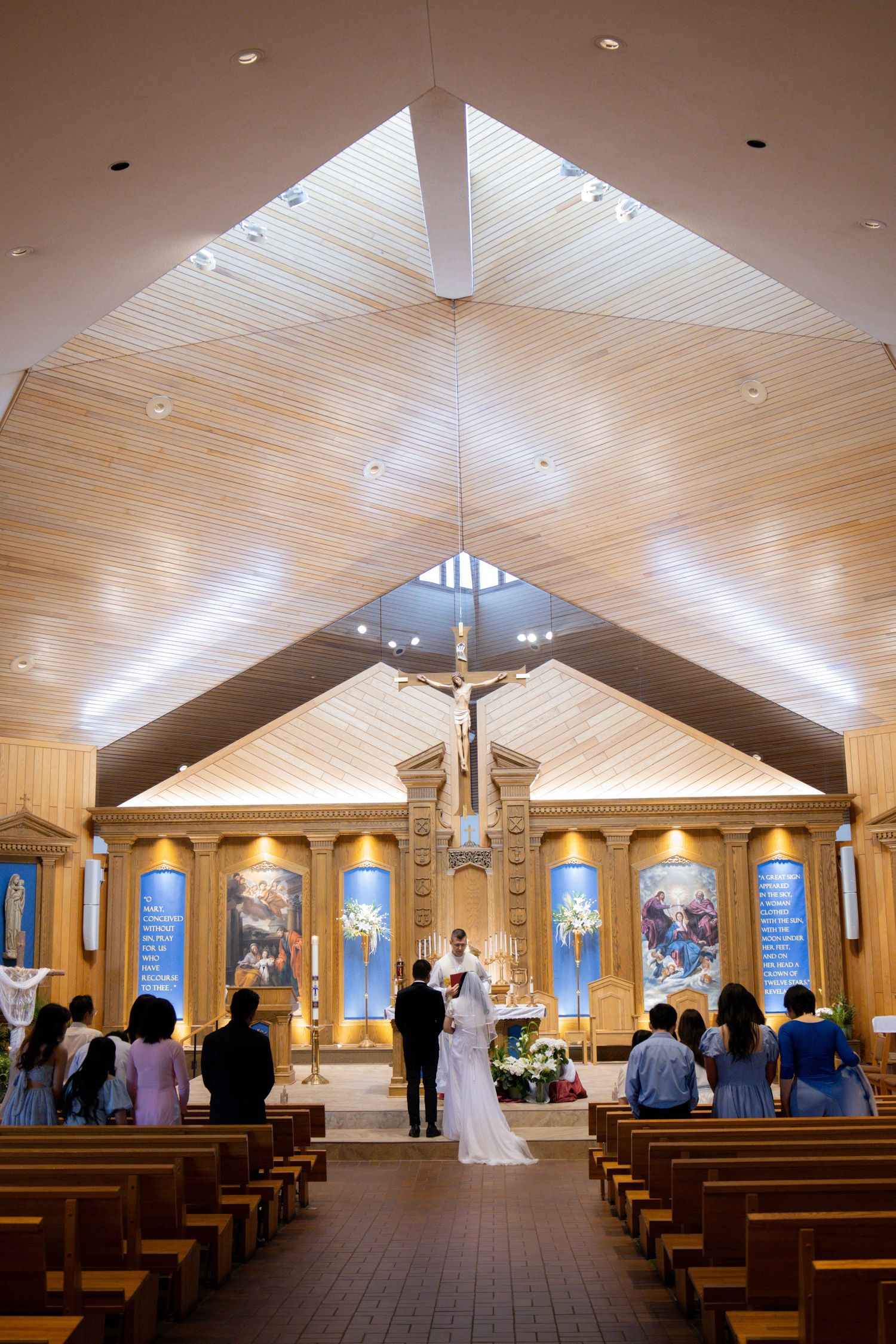 A panoramic view of a modern church interior with wooden pews and vaulted ceilings illuminated by natural light.