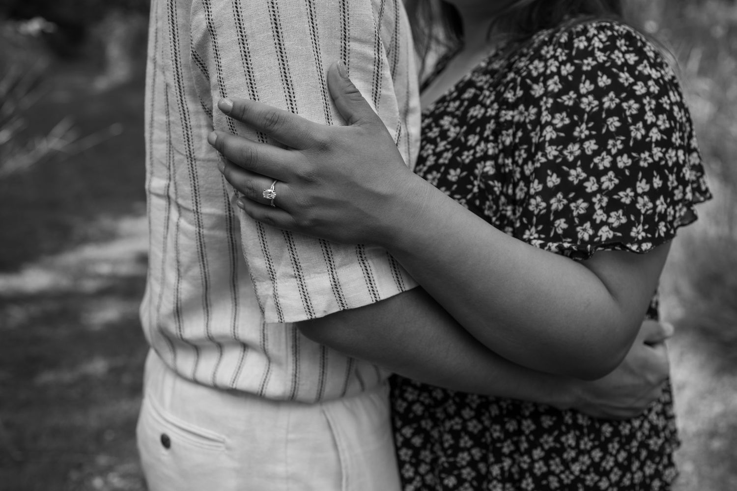 A romantic black and white photo of a couple embracing shows only their torsos wearing patterned and striped clothing.