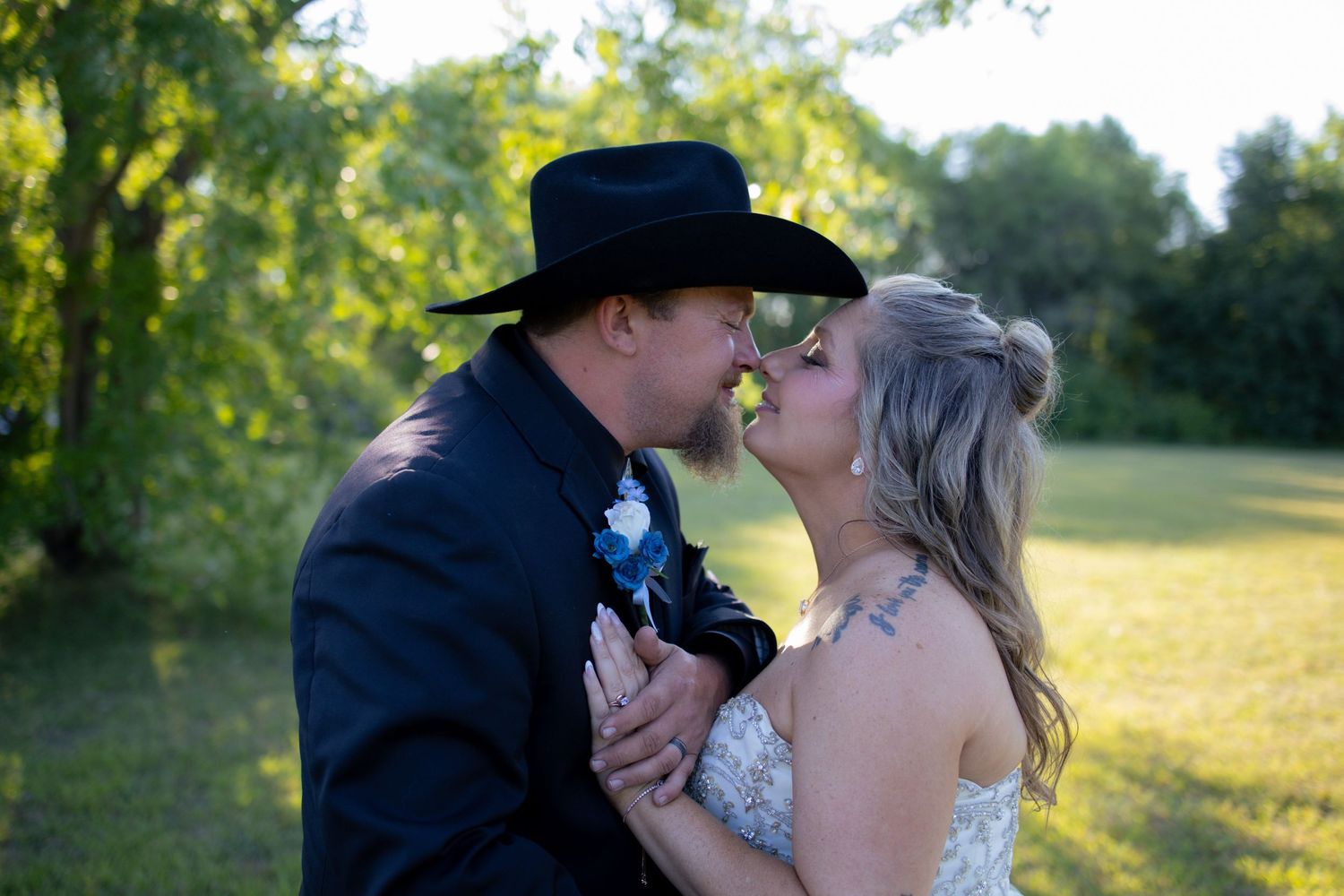 A couple shares a romantic kiss in a sunny meadow during a golden hour photo session.