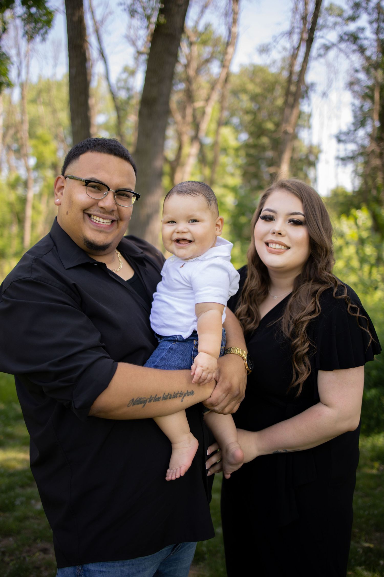 A family in matching black outfits poses together outdoors near trees in a series of candid shots.