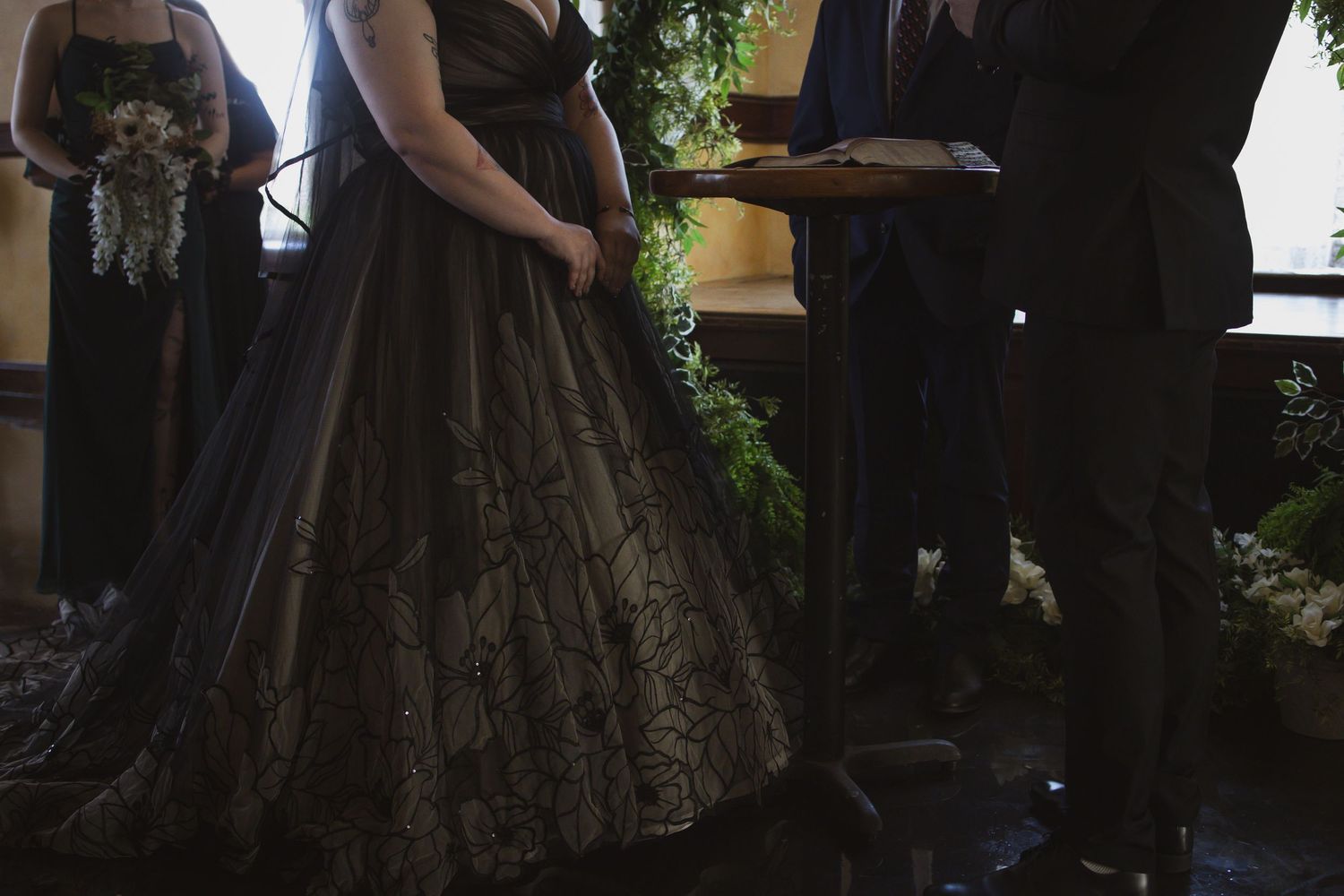 An elegant black lace ballgown dress is shown in a dimly lit room during a formal event.