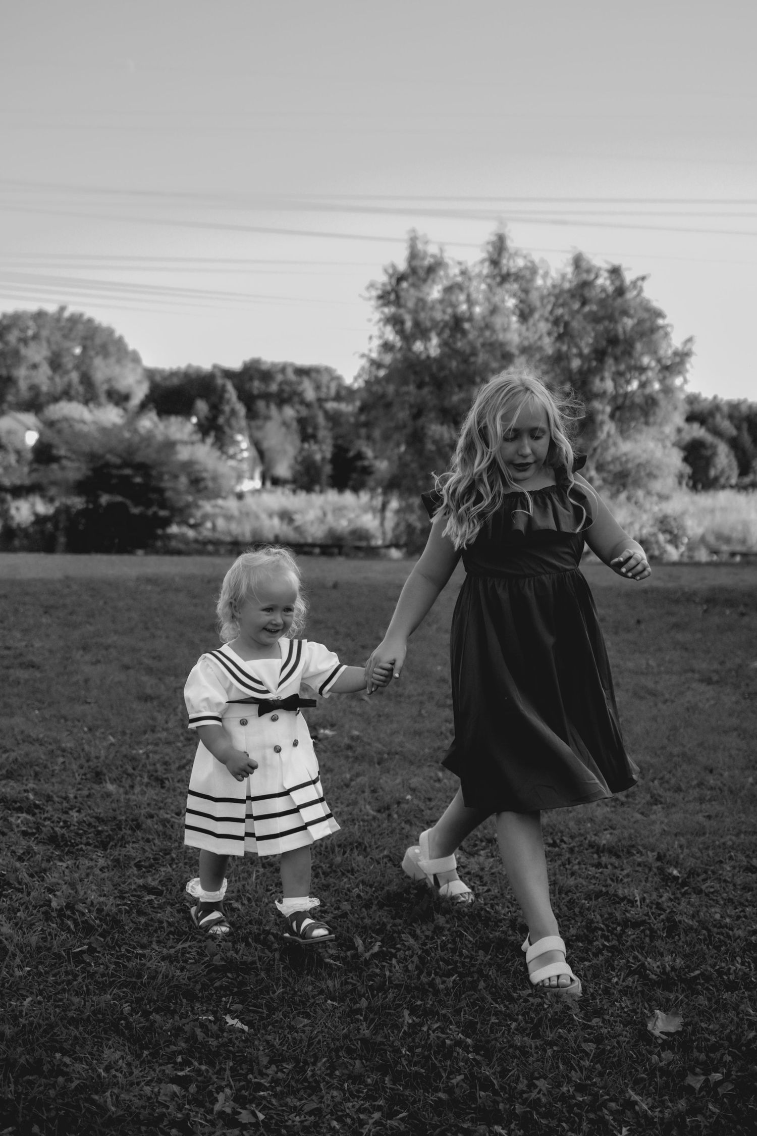 Black and white photos show two children playing and running together in a grassy field.