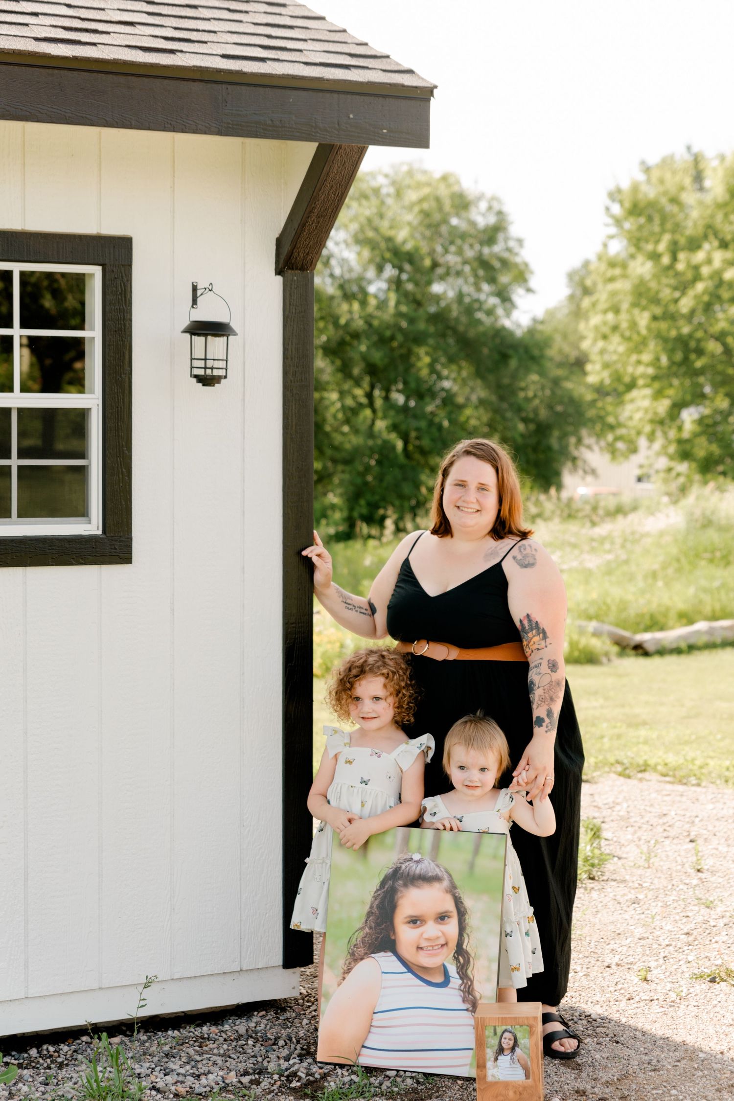 A group portrait next to a white house exterior with a decorative lantern and black window trim.
