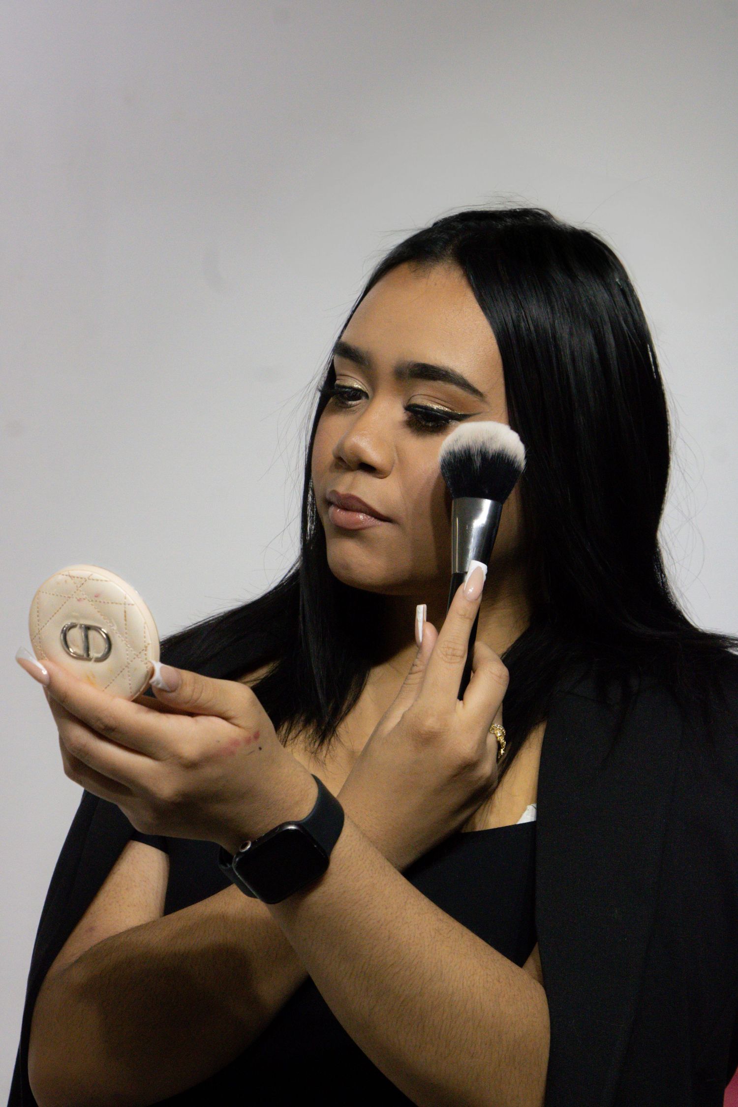 Multiple images show someone applying makeup using a round cosmetic powder compact and brush against a dark background.
