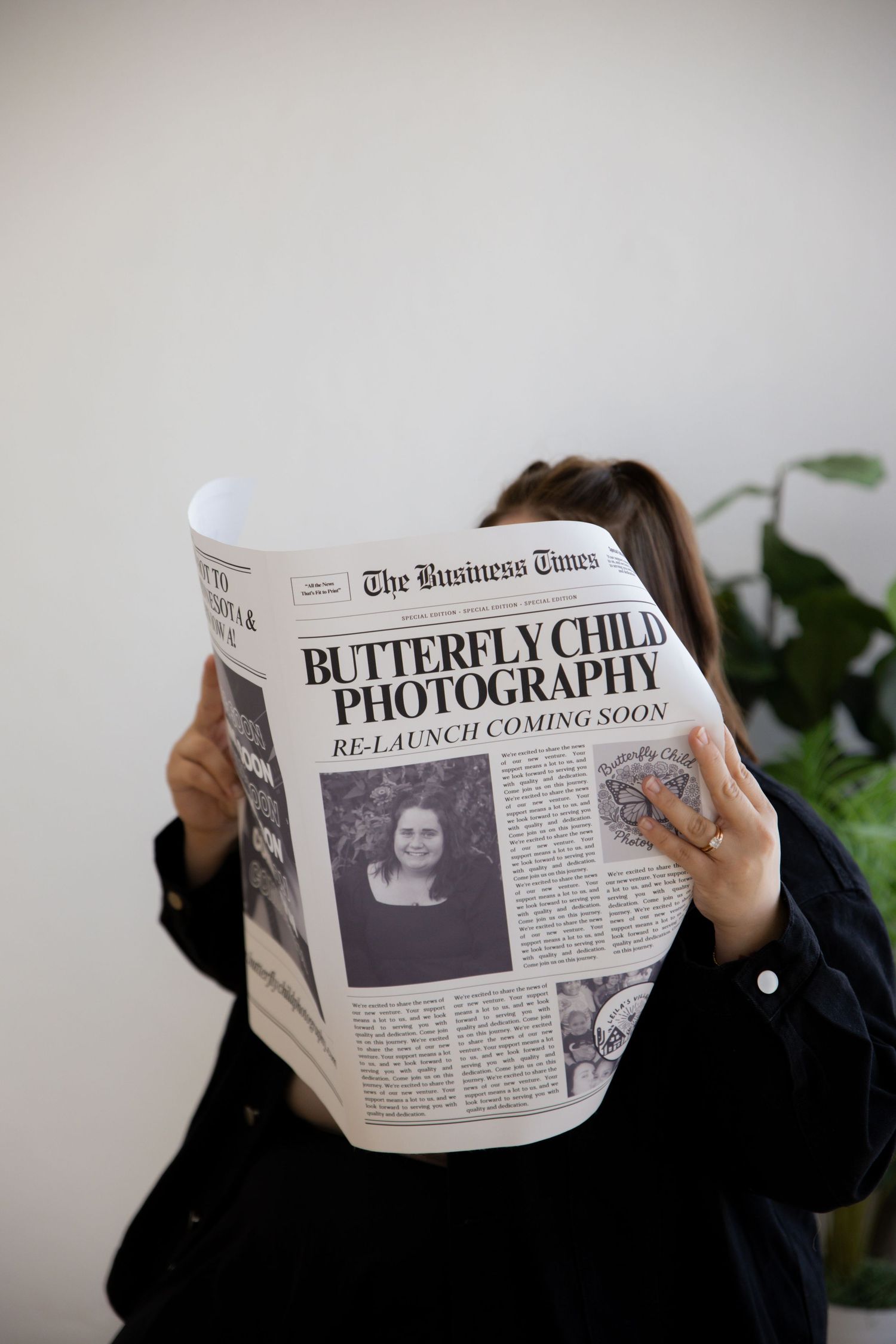 Someone holds up a newspaper with the headline 'Butterfly Child Photography' while reading behind it.