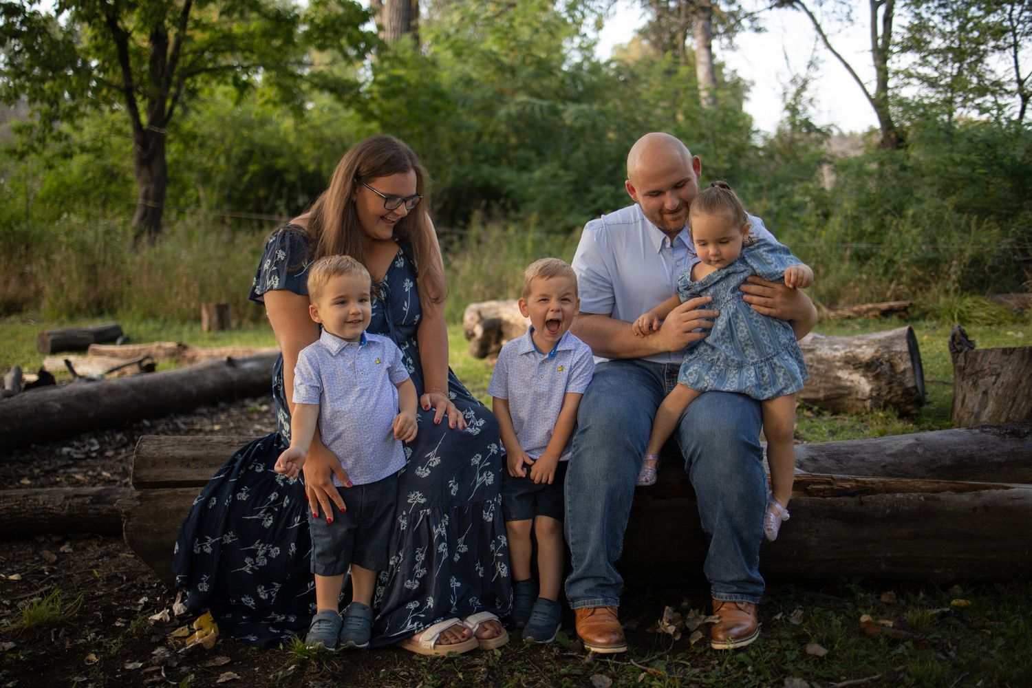 A series of candid shots of loved ones sitting and playing on fallen logs in a wooded outdoor setting during golden hour.