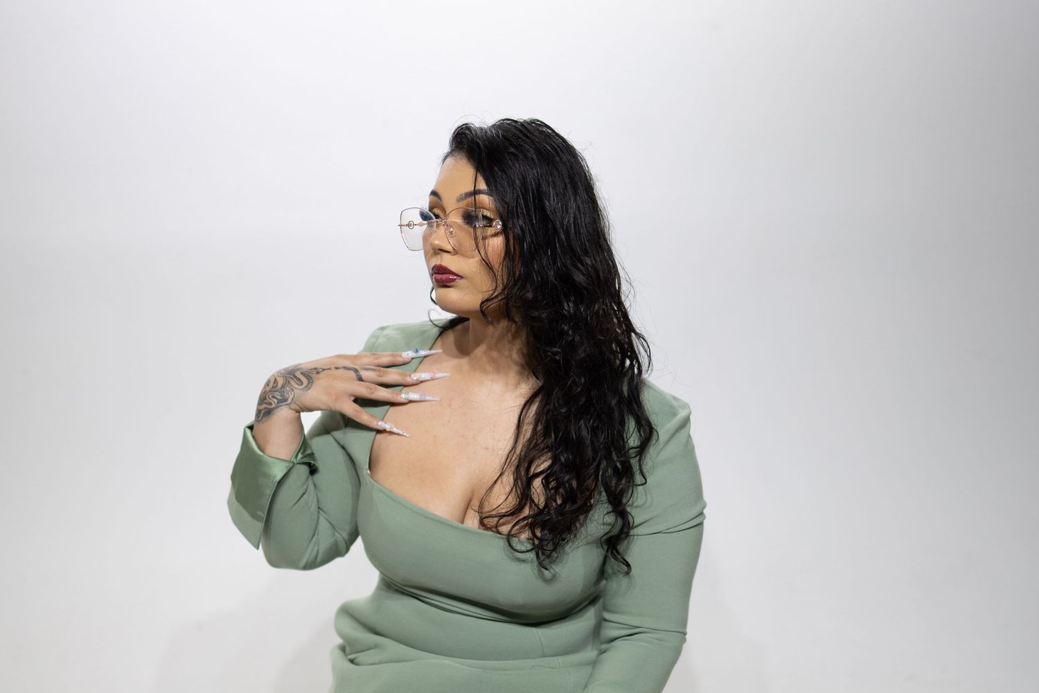 Person in sage green sweater poses expressively against white backdrop in multiple artistic shots.