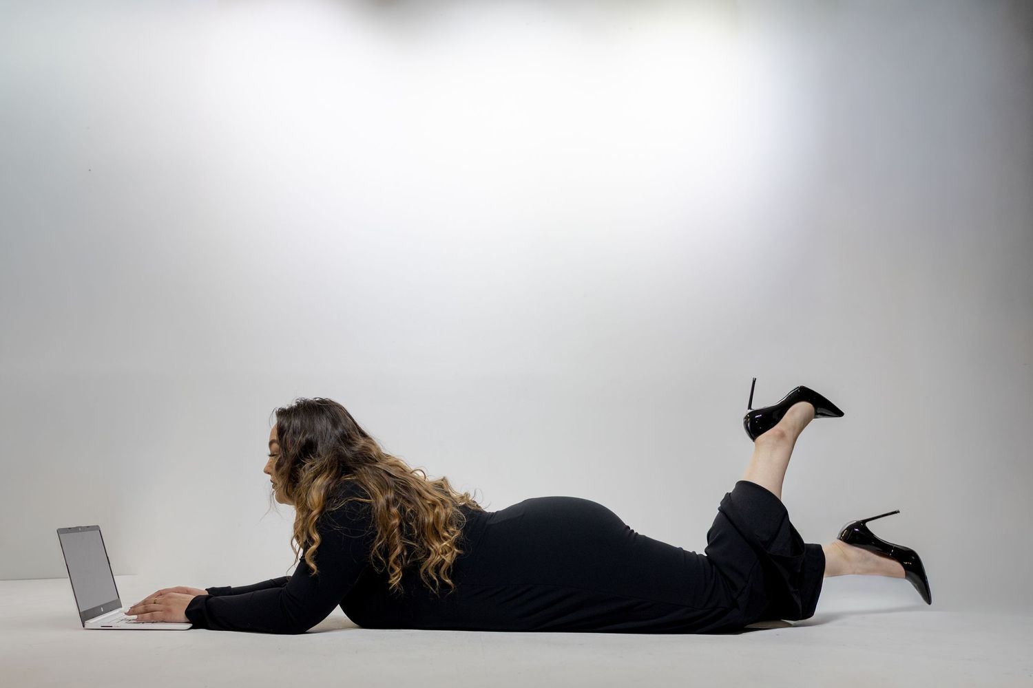 Person lying on floor with laptop showing progression of work postures from sitting to lying down.