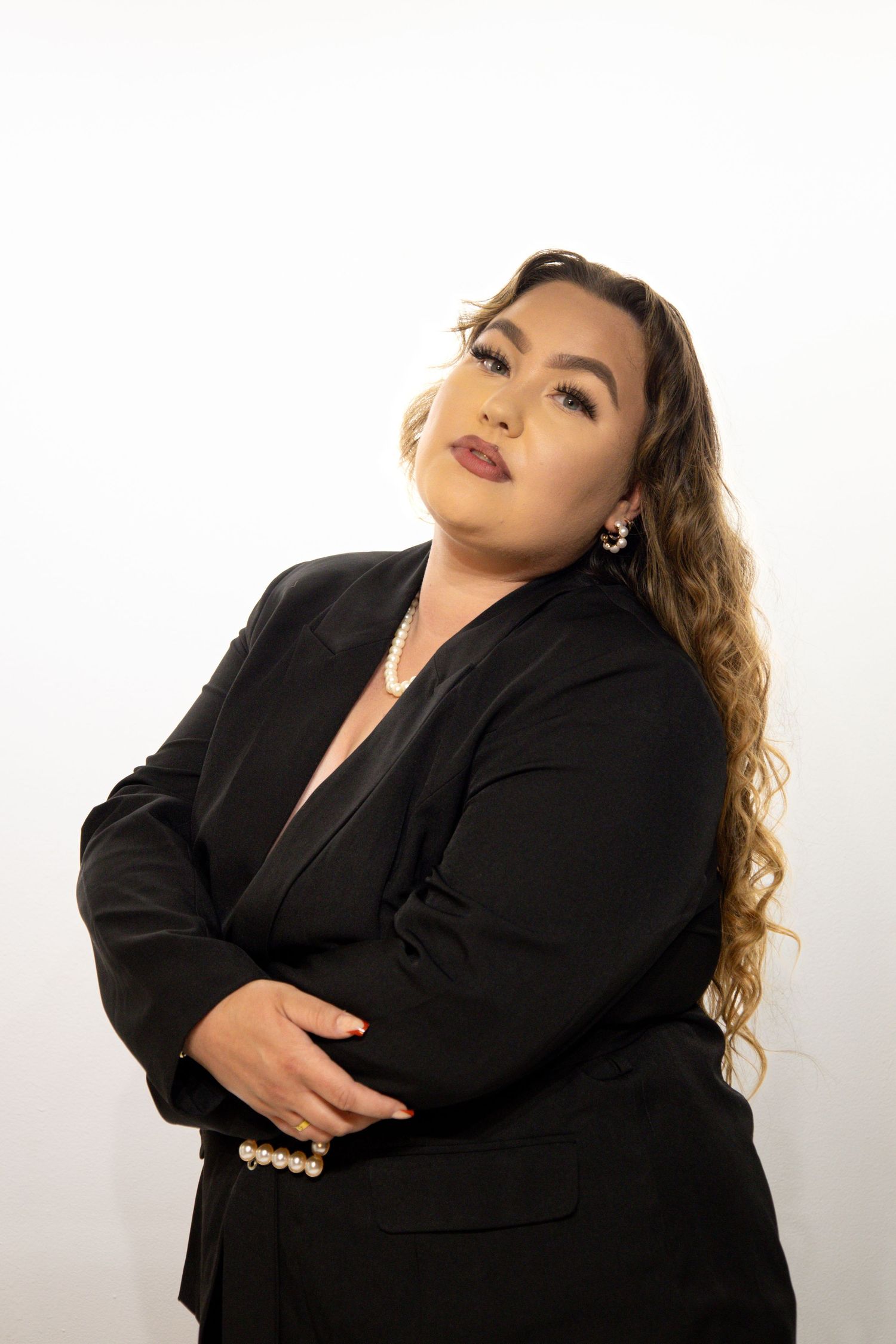 Professional studio portrait of a person in a black blazer posing confidently against a white background.