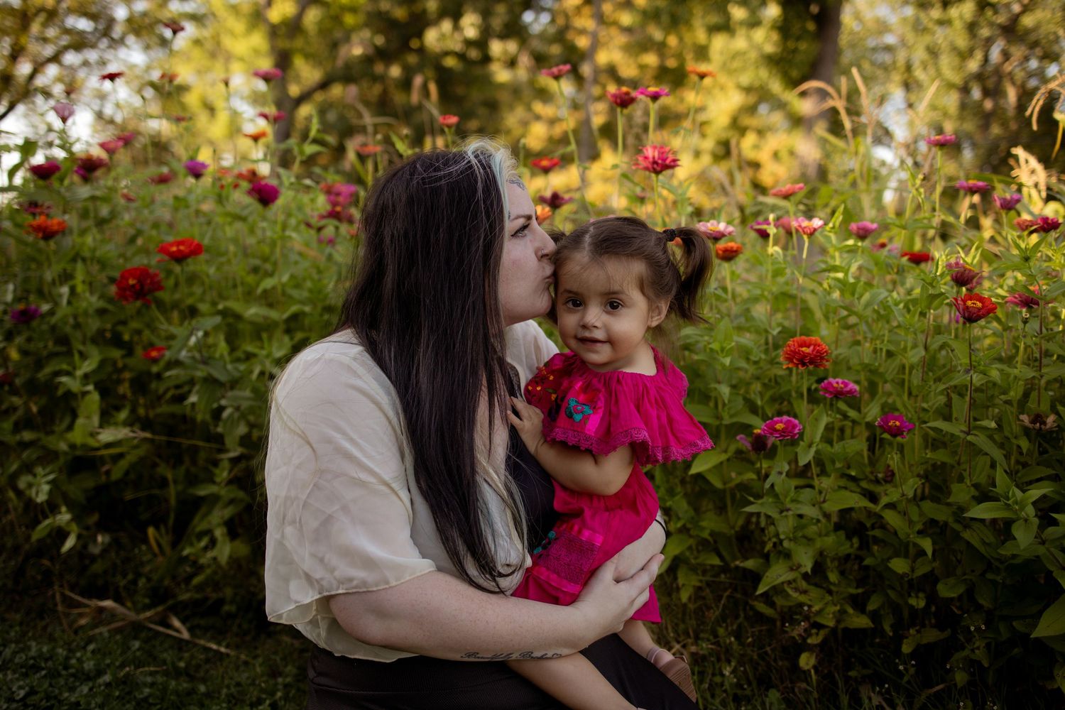 People enjoying a warm autumn day together in a garden with vibrant red flowers and golden foliage.