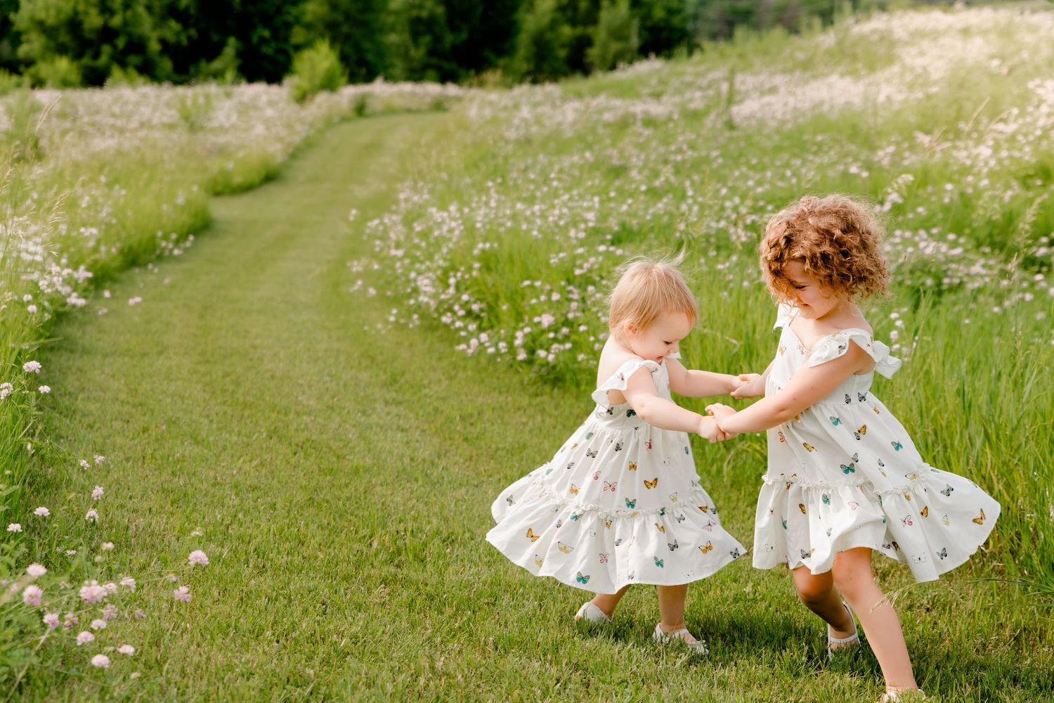 A child in a white dress walking through a wildflower meadow on a sunny summer day.
