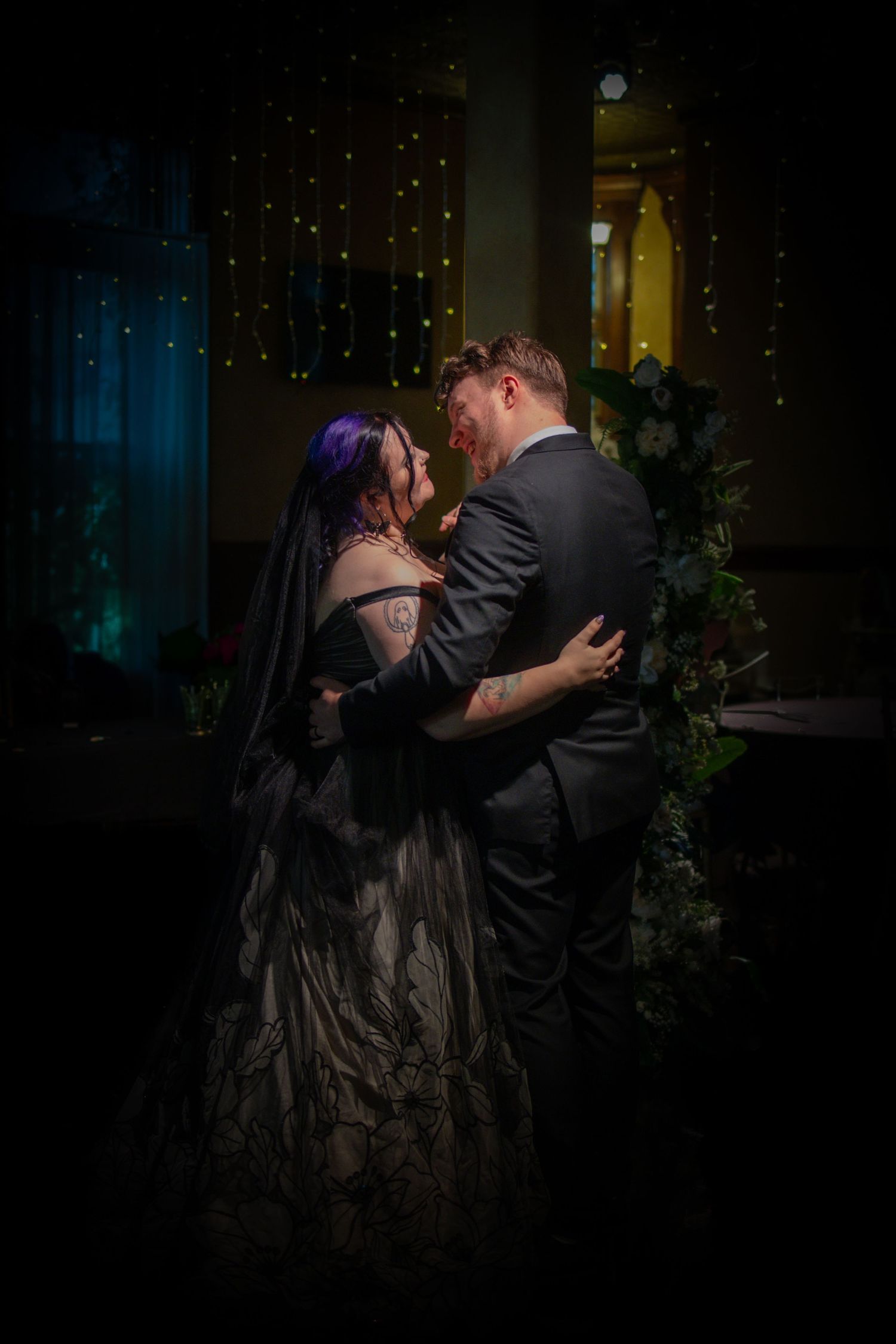 A couple dances intimately in dramatic low-key lighting with moody blue tones.