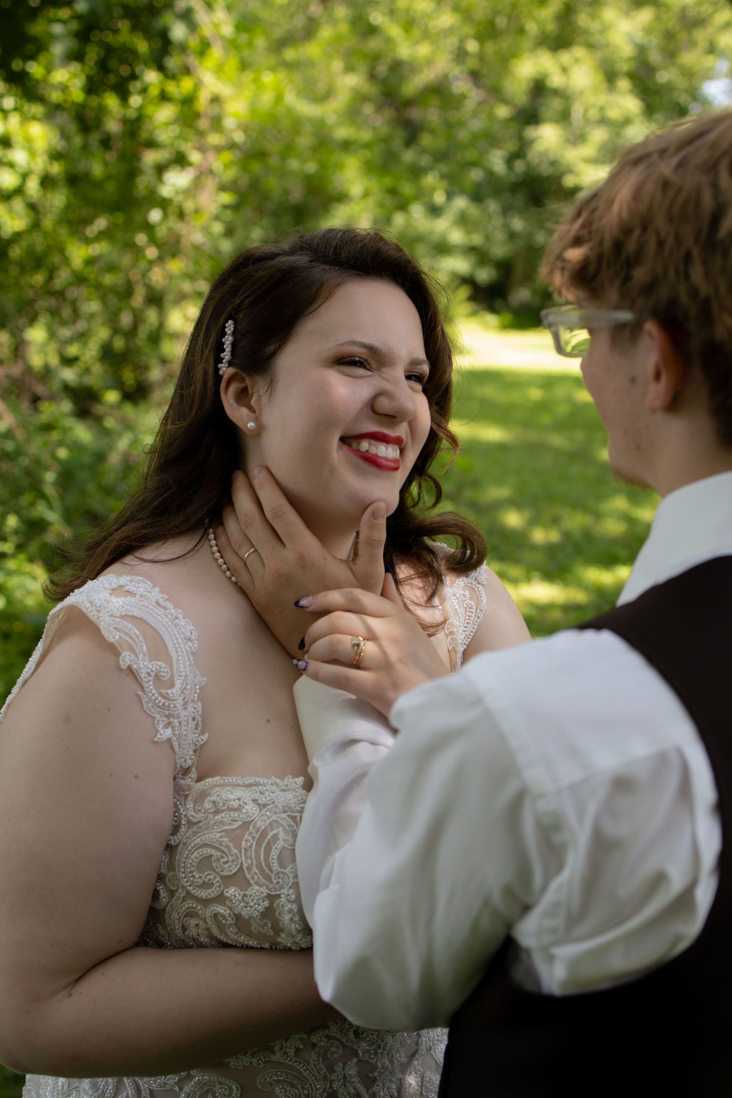 A couple shares a sweet moment together outdoors surrounded by greenery on their wedding day.