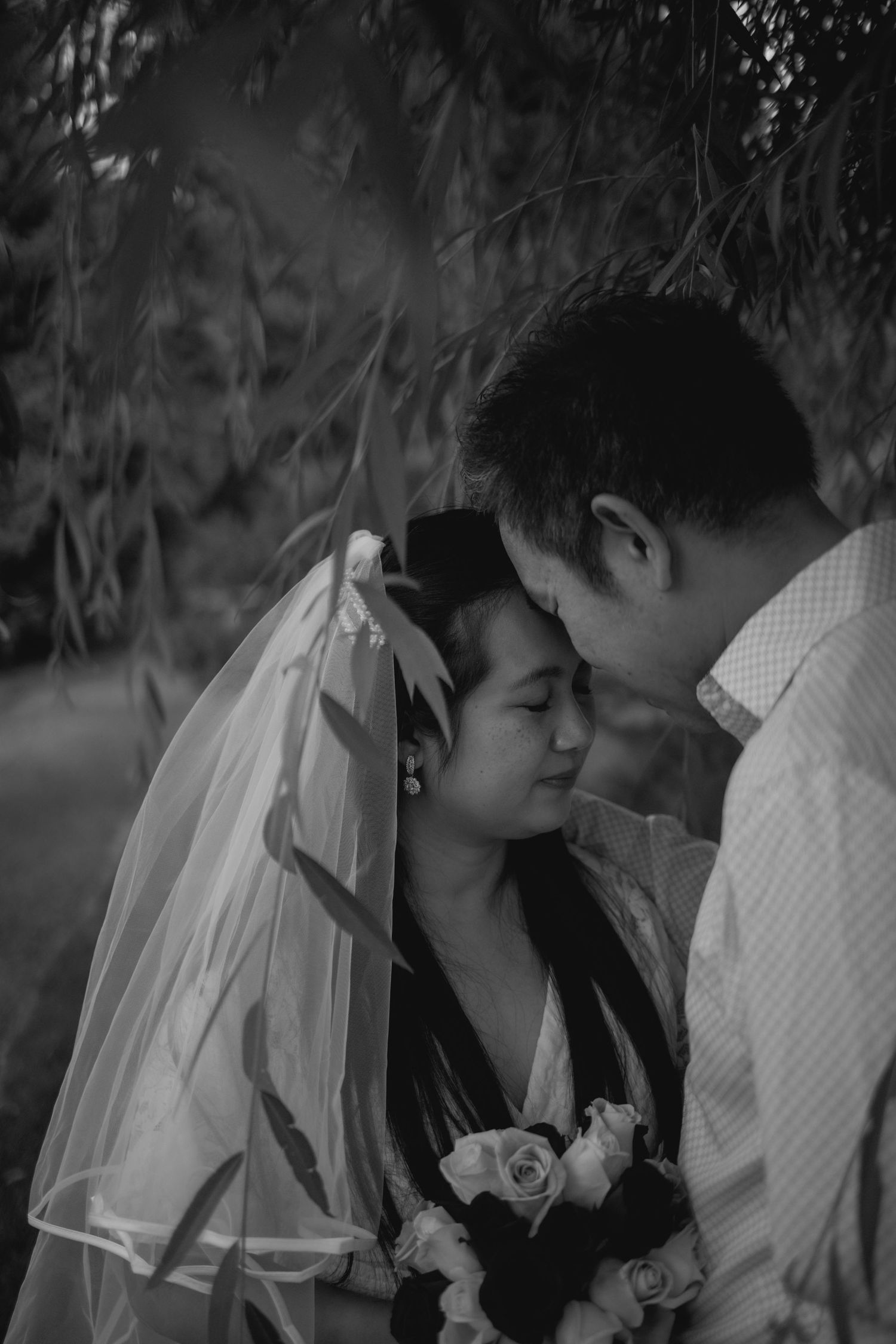 A romantic black and white photo sequence shows a couple embracing under willow branches with the bride wearing a veil.