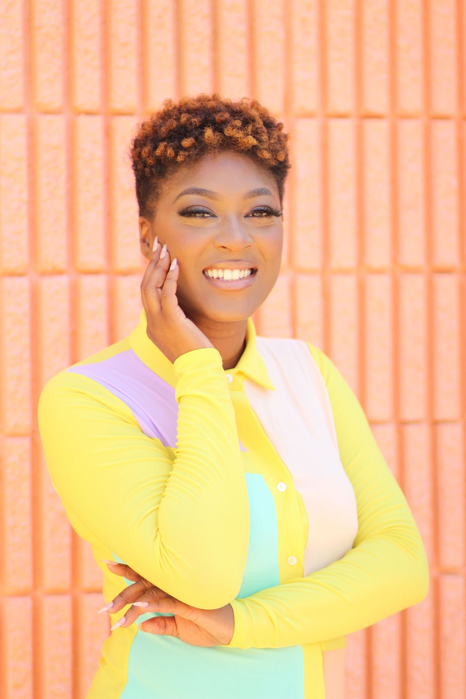 Cheerful fashion portrait against coral wall wearing yellow and pastel color-block outfit.