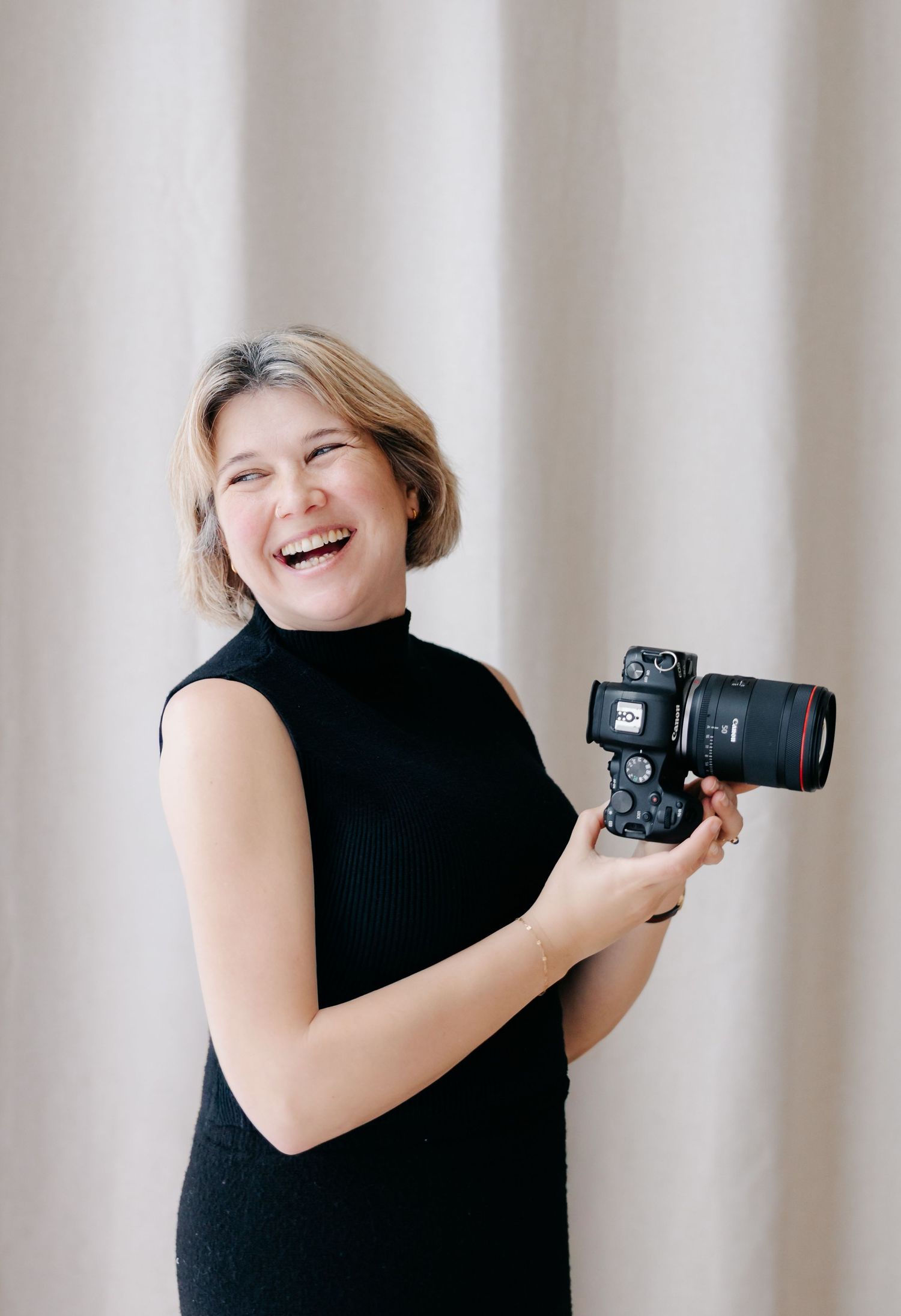 A sequence of four photos showing a photographer in a black sleeveless top laughing while holding a camera.