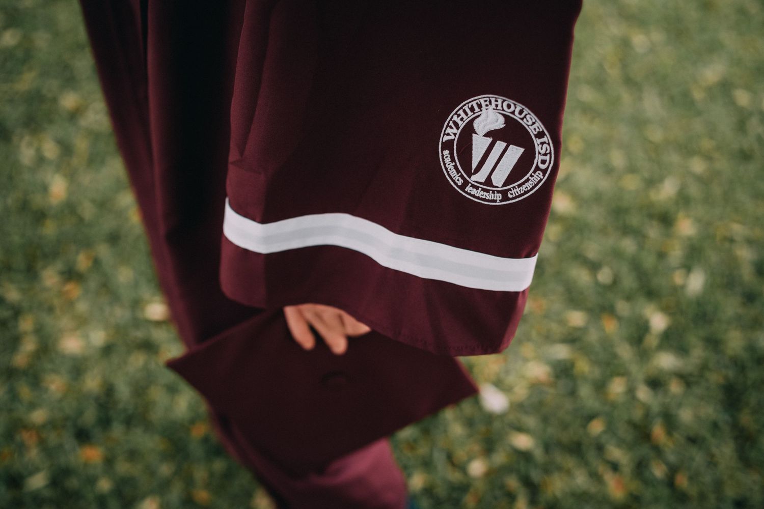 Maroon tracksuit with white stripe and circular logo detail on sleeve.