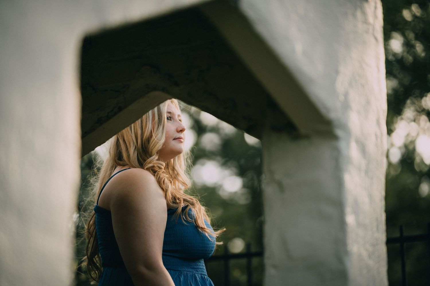 An artistic portrait taken under architectural elements with soft natural lighting.