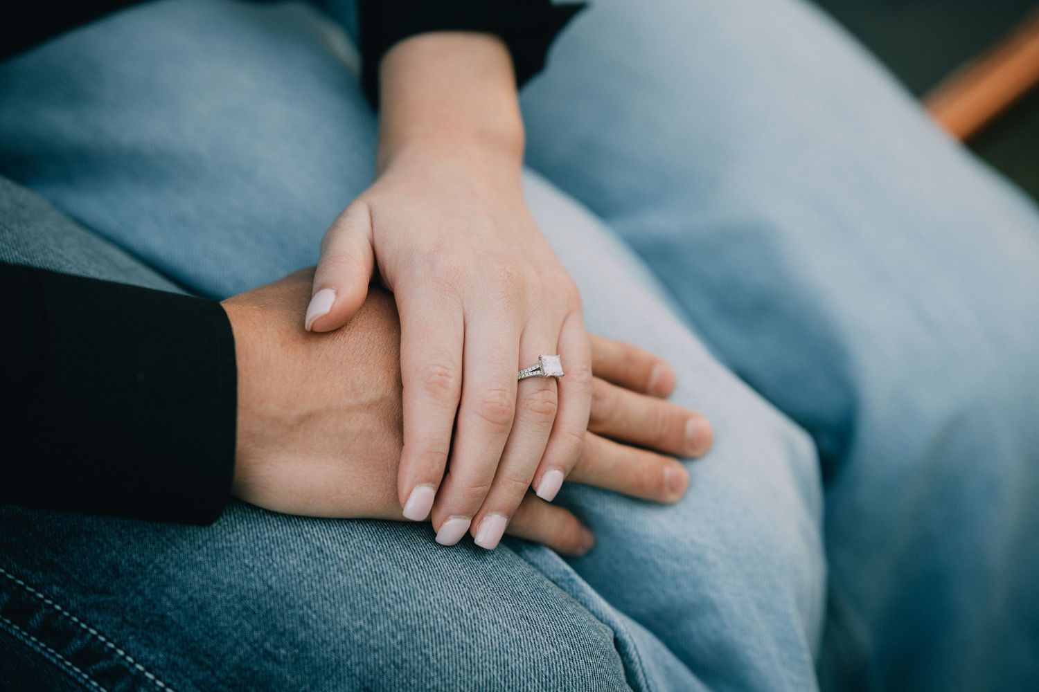 Hands clasped together in an intimate moment with wedding rings visible.