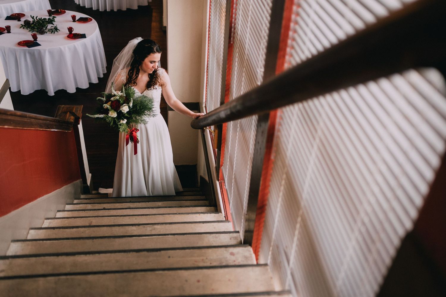 A figure in a flowing white dress descends a staircase in dramatic lighting.