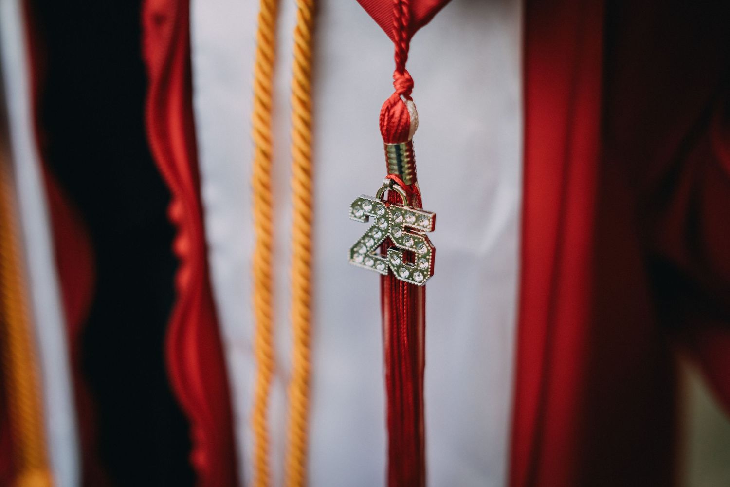 A decorative red graduation tassel with crystal charm hanging against a white background.