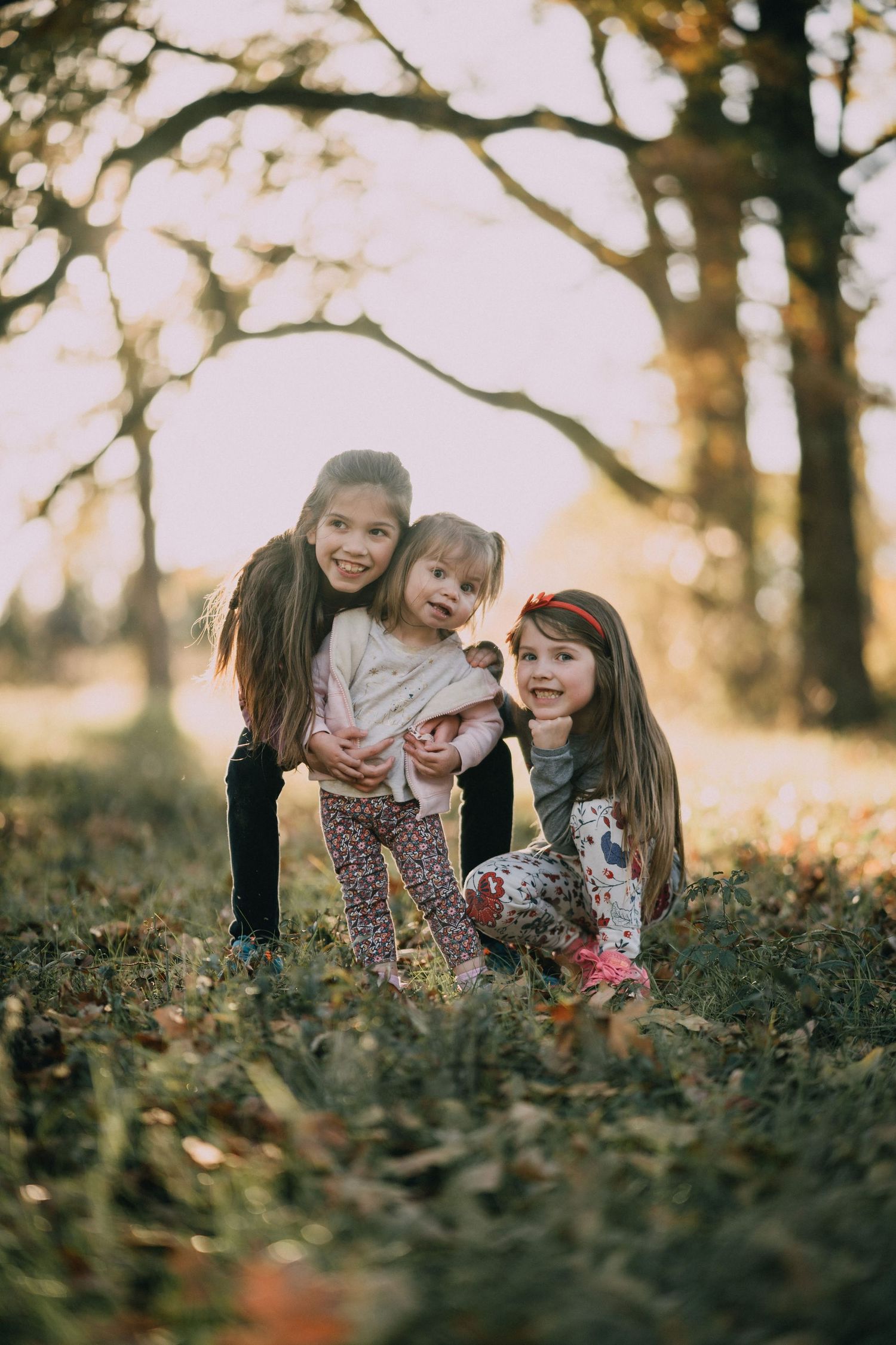 Children playing and laughing together in fallen autumn leaves during golden hour.