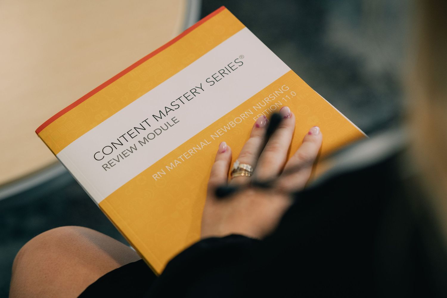 Close-up of hands holding academic course materials with yellow cover.
