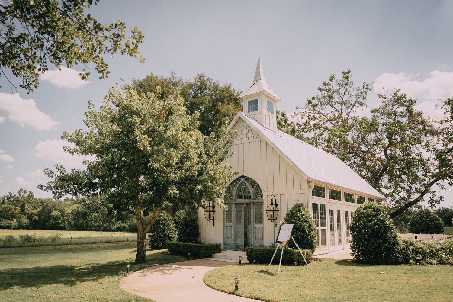 White country church with steeple photographed from distance on sunny day.