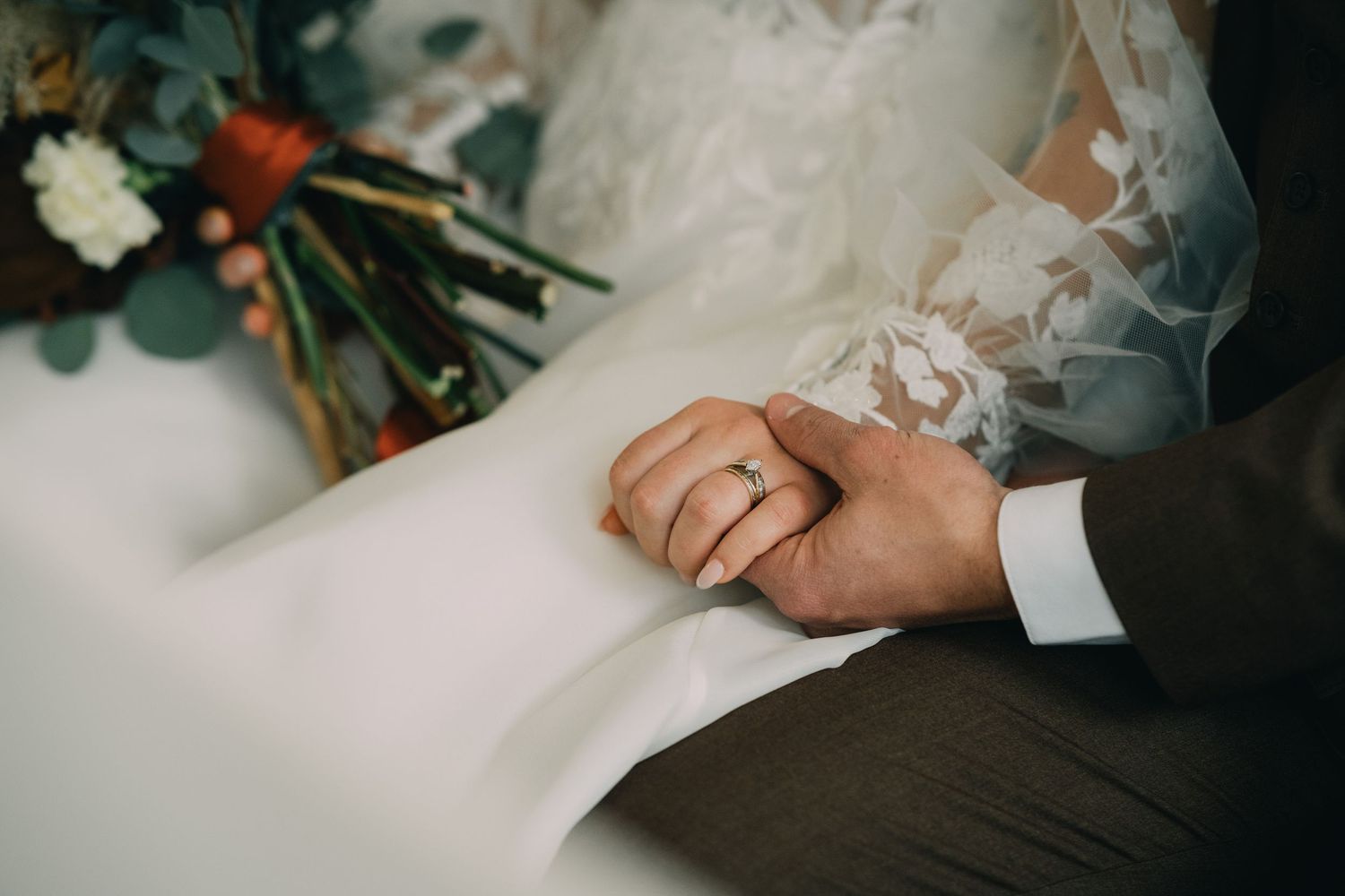 Elegant wedding dress details with floral bouquet elements in soft focus.